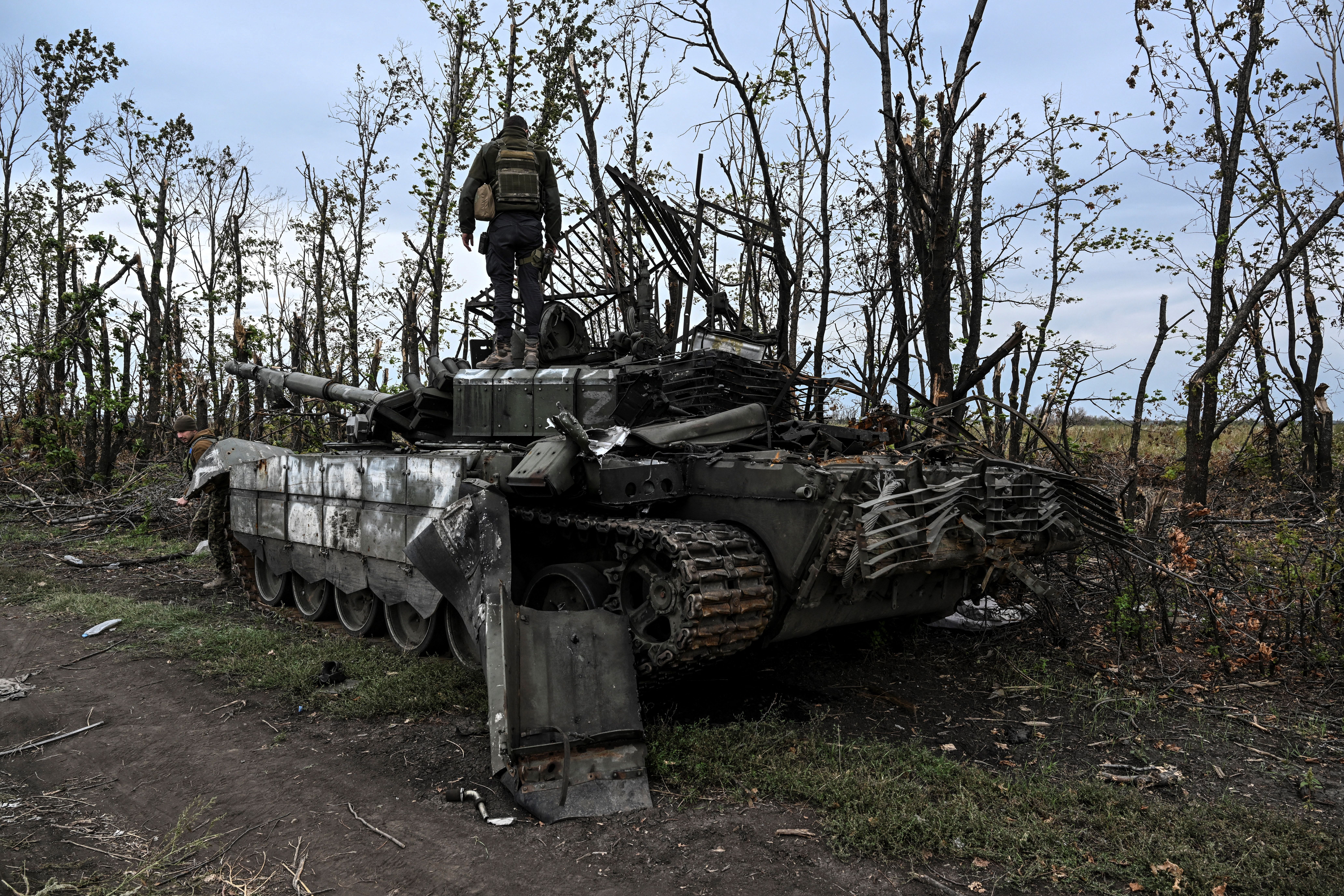 Un soldado ucraniano de pie sobre un tanque ruso abandonado cerca de un pueblo en las afueras de Izyum, (Juan BARRETO / AFP)