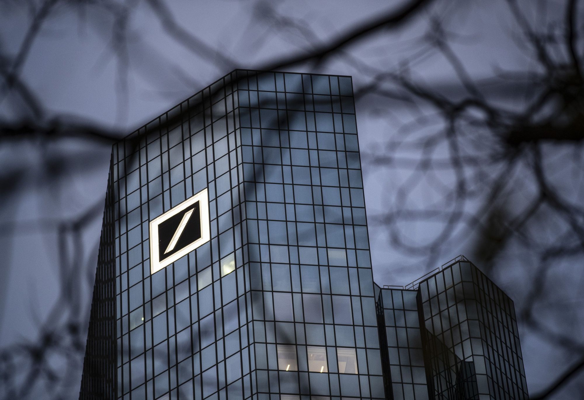 A logo sits on the Deutsche Bank AG headquarters at dawn in Frankfurt, Germany, on Tuesday, Dec. 10, 2019. Deutsche Bank said revenue from fixed-income trading is up this quarter while warning that its mid-term profitability goal is now more ambitious given the outlook for interest rates. Photographer: Alex Kraus/Bloomberg