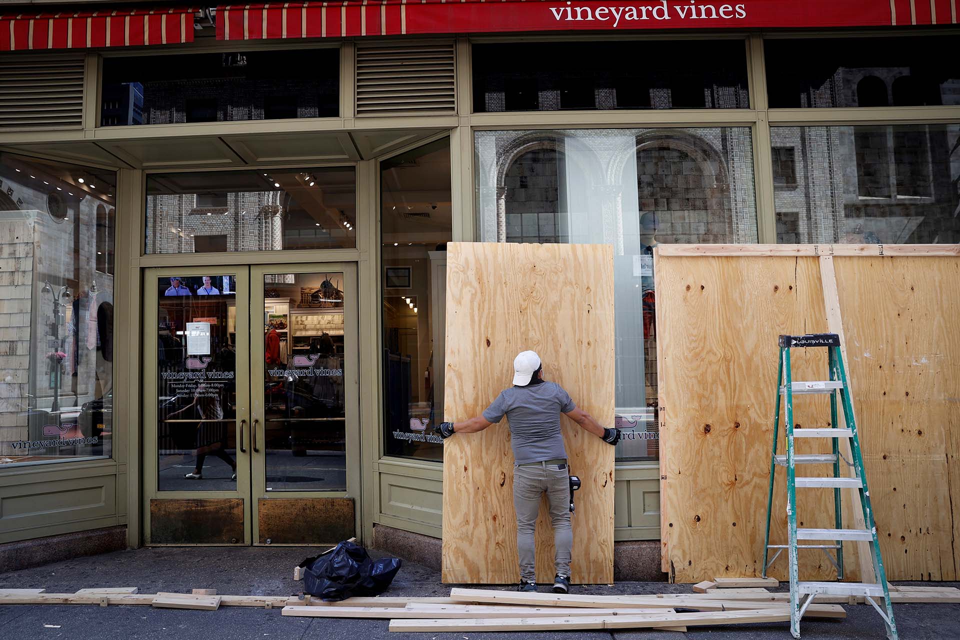 Un trabajador quita las maderas que protegieron las vitrinas de Vineyard Vines en Manhattan, durante las protestas contra el racismo de la última semana (REUTERS)