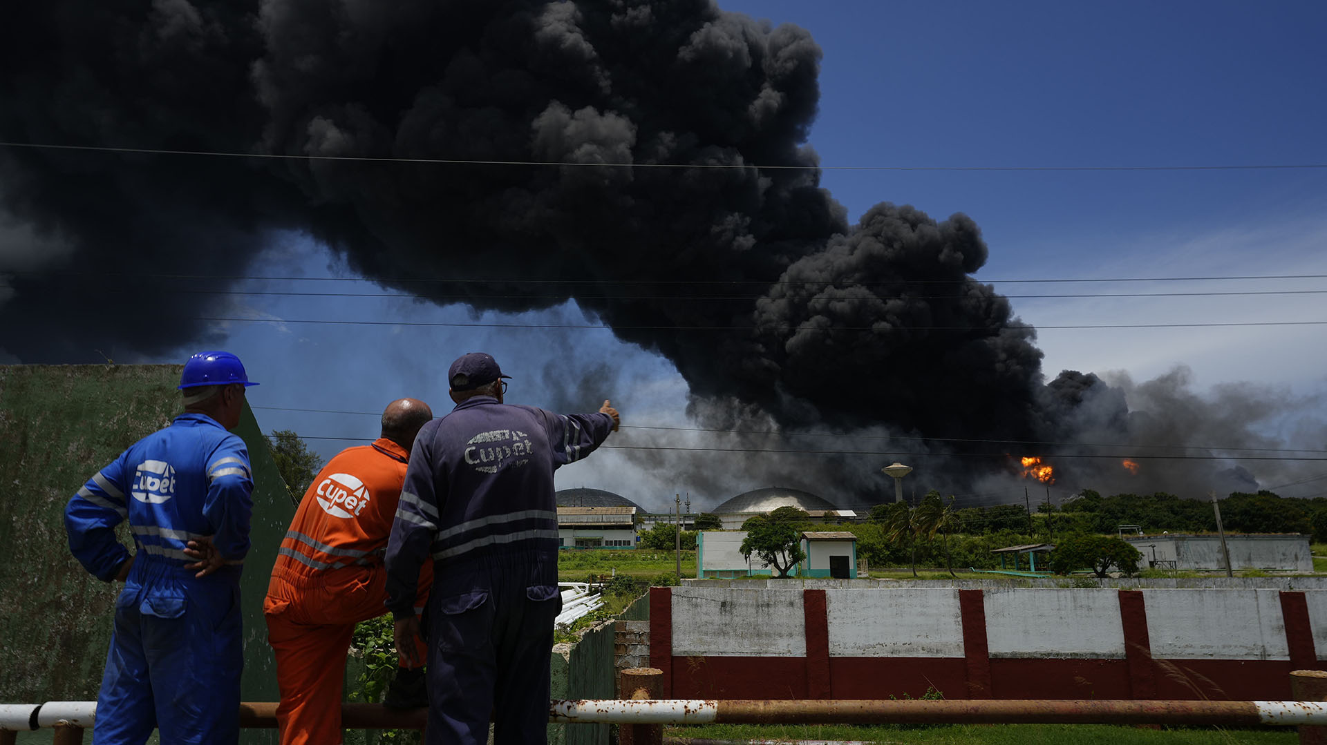 Workers of the Cuban Petroleum Union (CUPET) observe a huge column of smoke rising from the Matanzas Superpetroleros Base (AP/Ramon Espinosa)