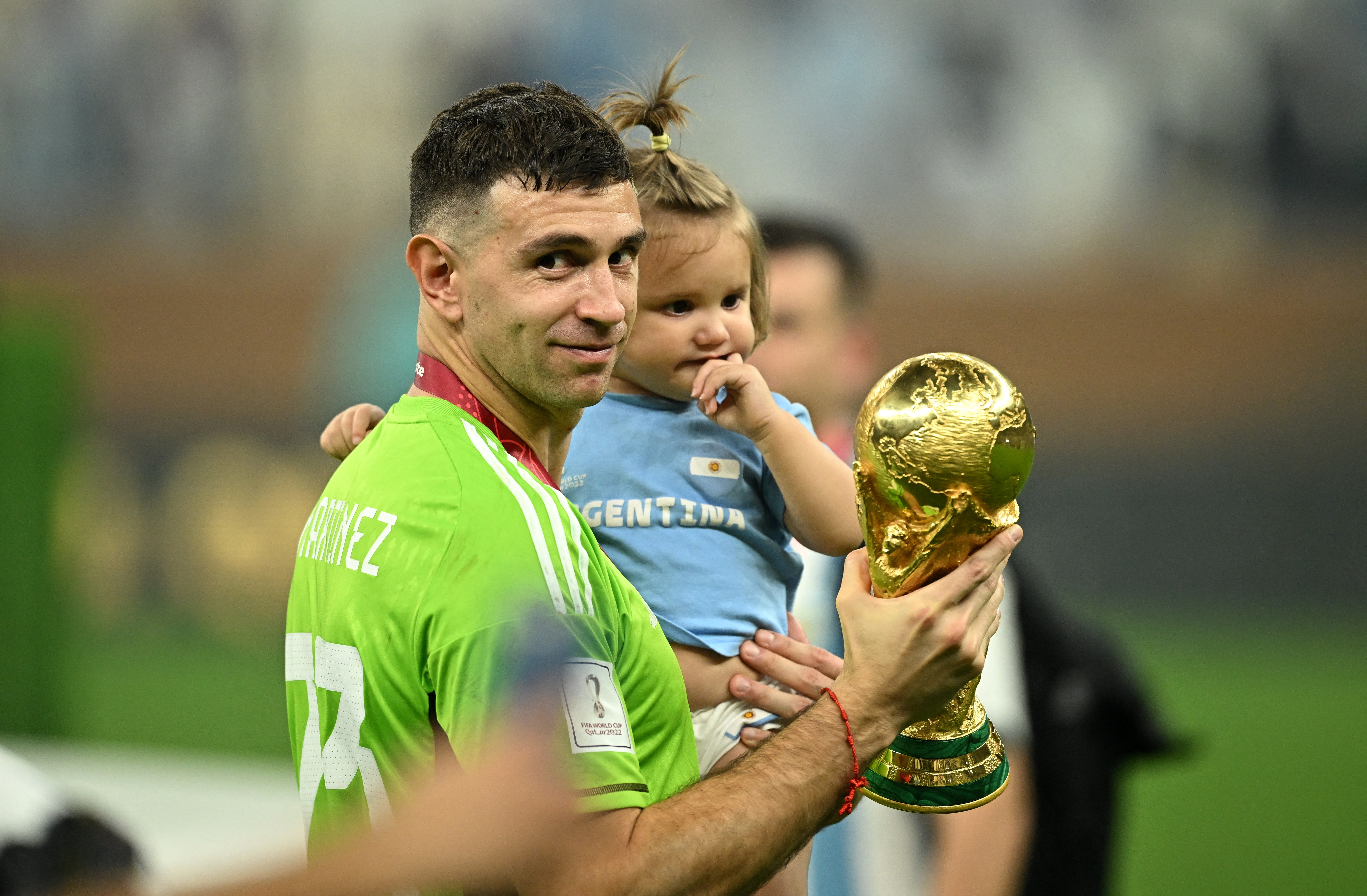 Soccer Football - FIFA World Cup Qatar 2022 - Final - Argentina v France - Lusail Stadium, Lusail, Qatar - December 18, 2022  Argentina's Emiliano Martinez celebrates with a child and the trophy after winning the World Cup REUTERS/Dylan Martinez
