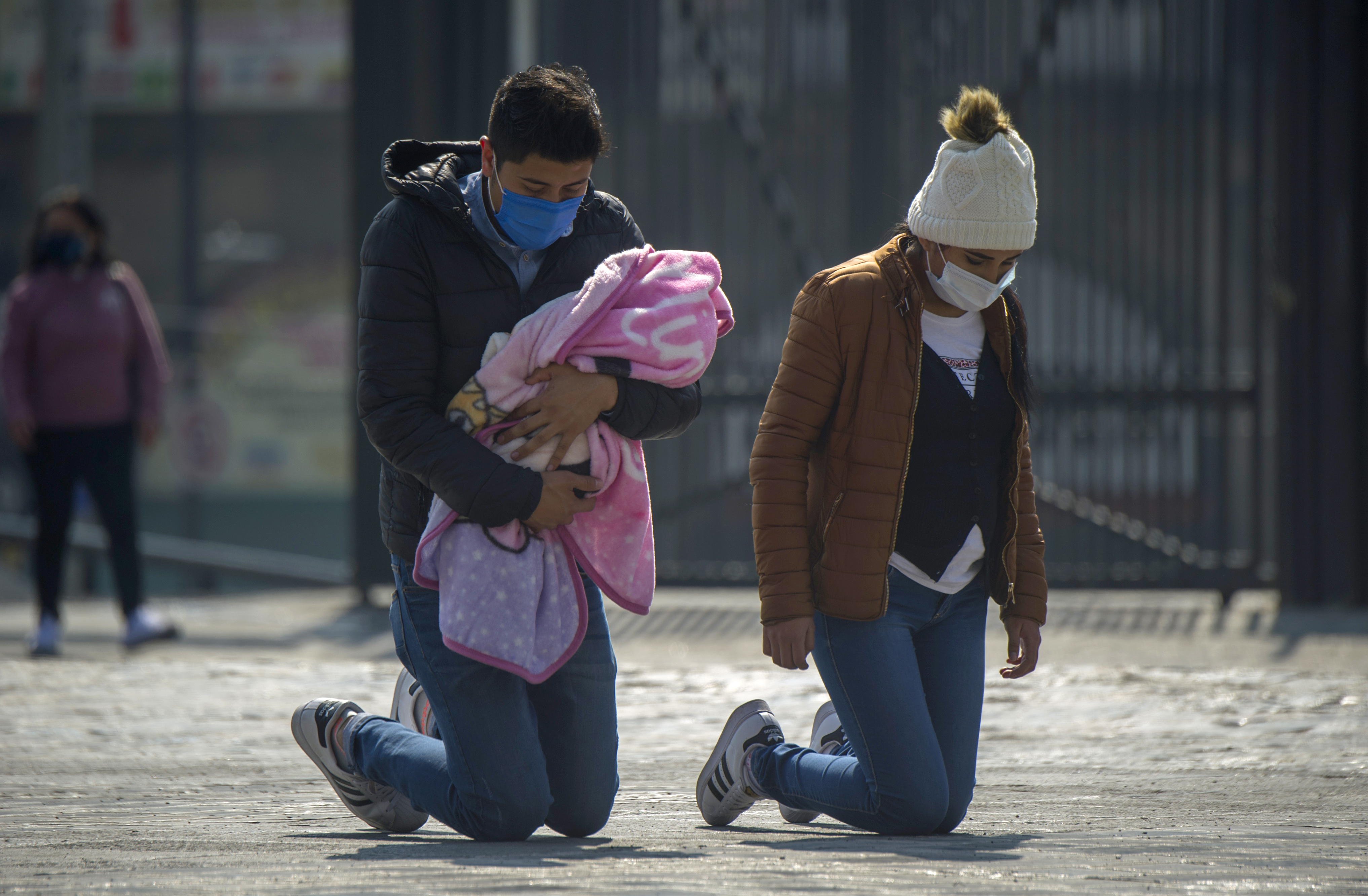 A couple with their baby walk on their kneels to the Basilica of Guadalupe in Mexico City, on December 7, 2020, amid the COVID-19 novel coronavirus pandemic. - The Basilica of Guadalupe will remain closed from December 10 to 13 during the festivities of the Virgen Morena to avoid crowds and minimize the risks of possible contagion of COVID-19 among pilgrims. (Photo by Claudio CRUZ / AFP)