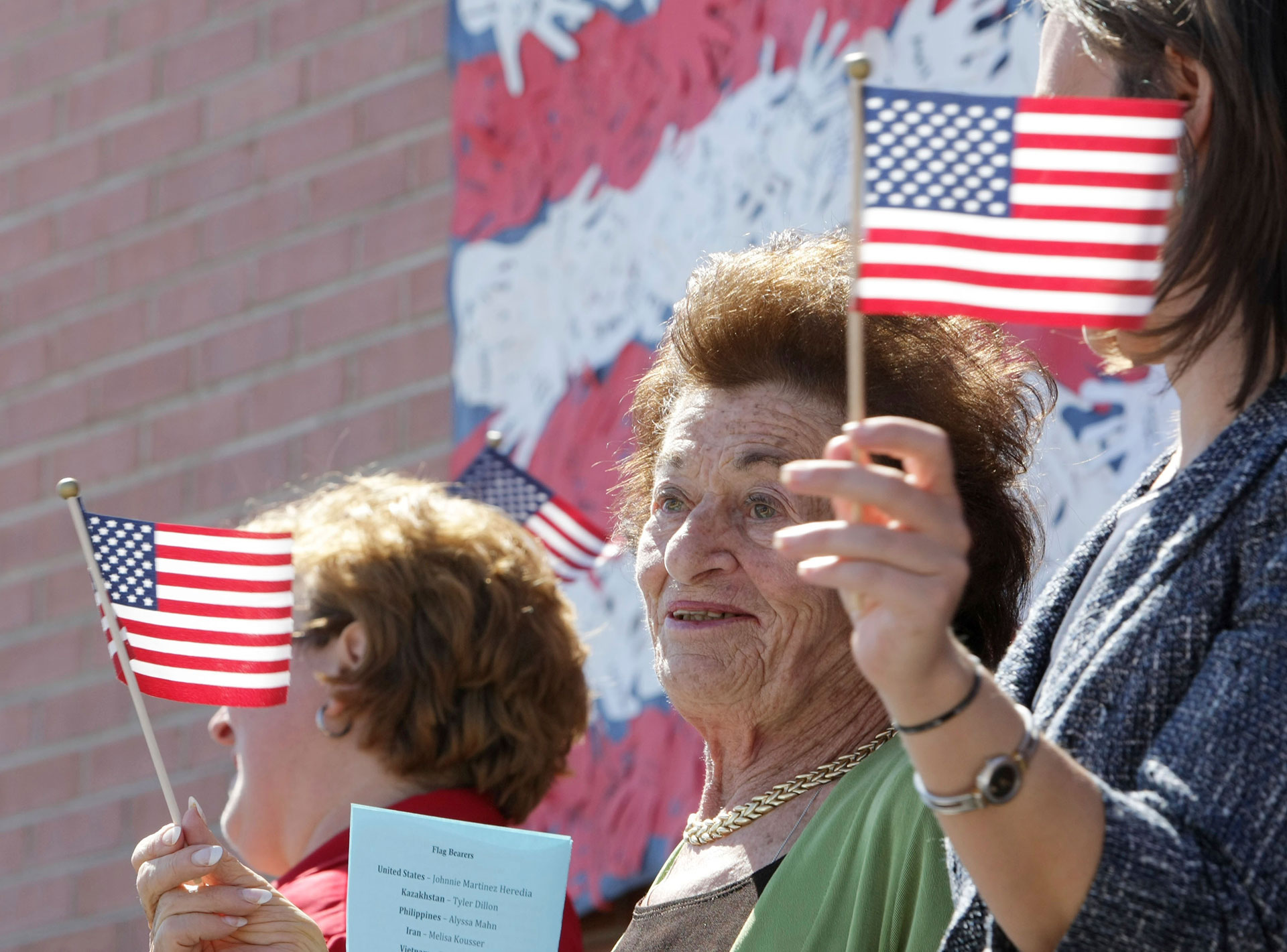 Gerda Weissmann Klein, en el centro, fundadora de Citizenship Counts y superviviente del Holocausto, y su nieta Alysa Ullman, agitan banderas durante una ceremonia de naturalización en la escuela Maryland de Phoenix el 11 de mayo de 2011.(Deirdre Hamill/The Arizona Republic via AP)