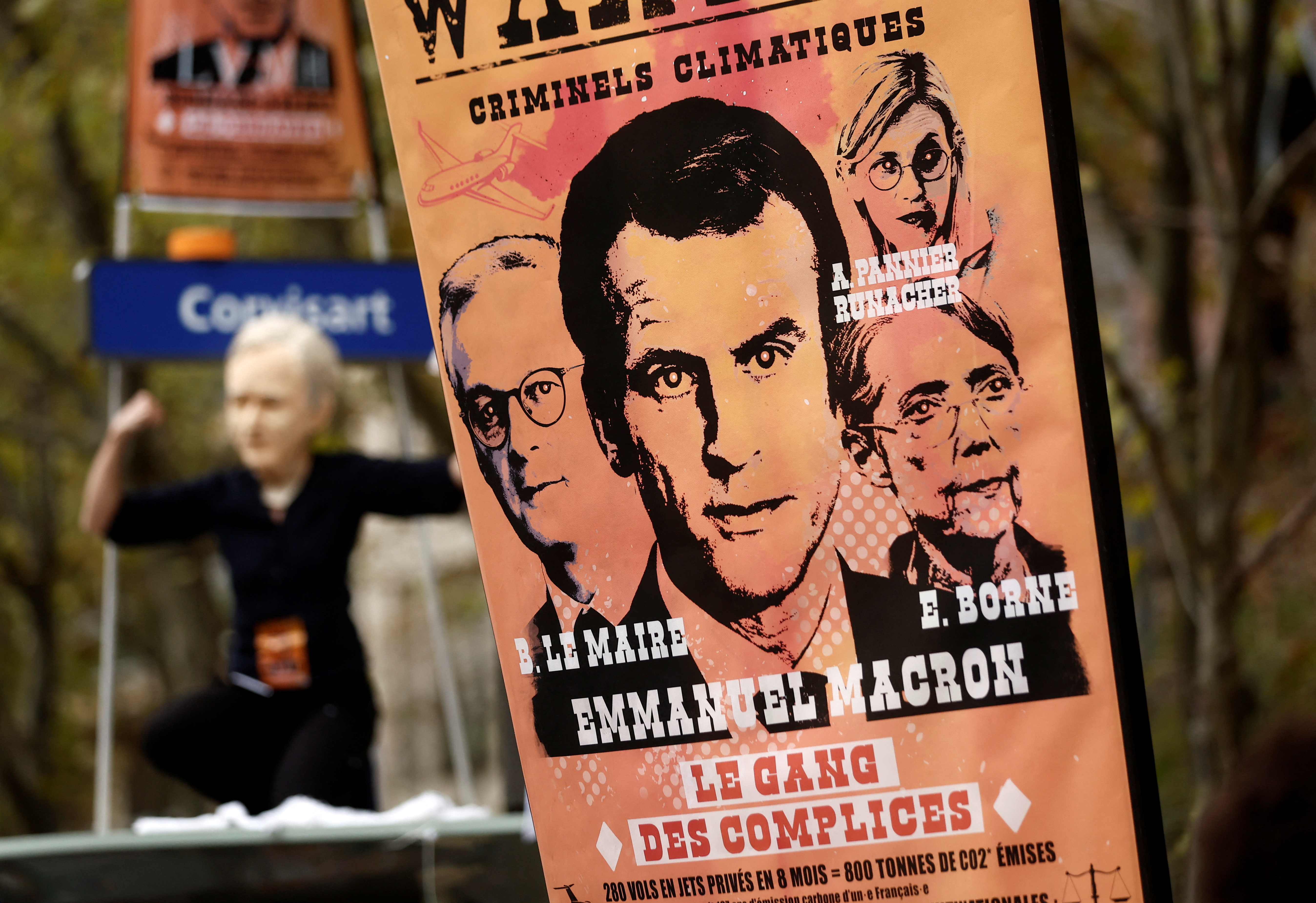Une pancarte avec un portrait du président français Emmanuel Macron est affichée lors de la manifestation à Paris aux côtés d'un manifestant portant un masque représentant Bernard Arnault, président de LVMH Moët Hennessy Louis Vuitton (REUTERS/Benoit Tessier)