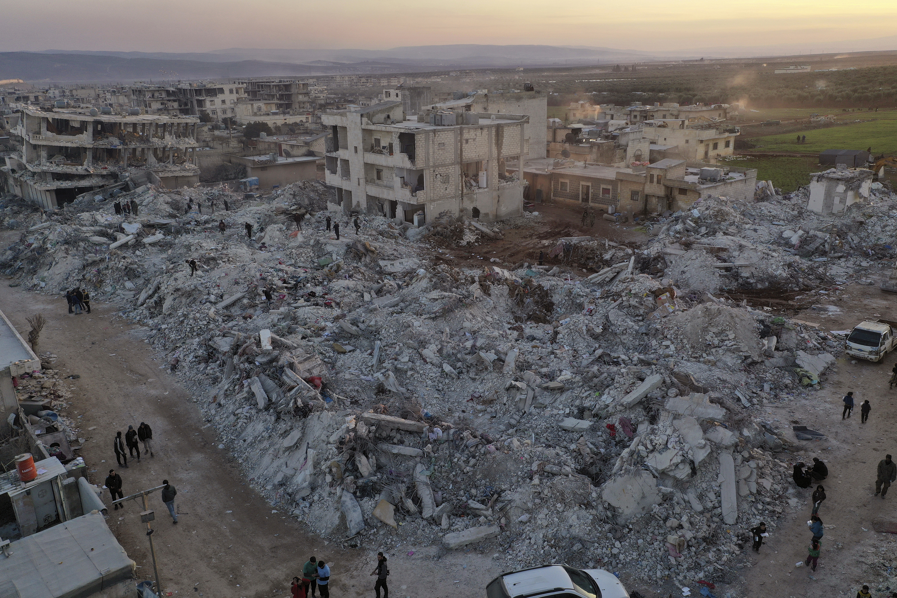 Varias personas caminan junto a edificios colapsados  en la provincia de Alepo, Siria (AP Foto/Ghaith Alsayed)