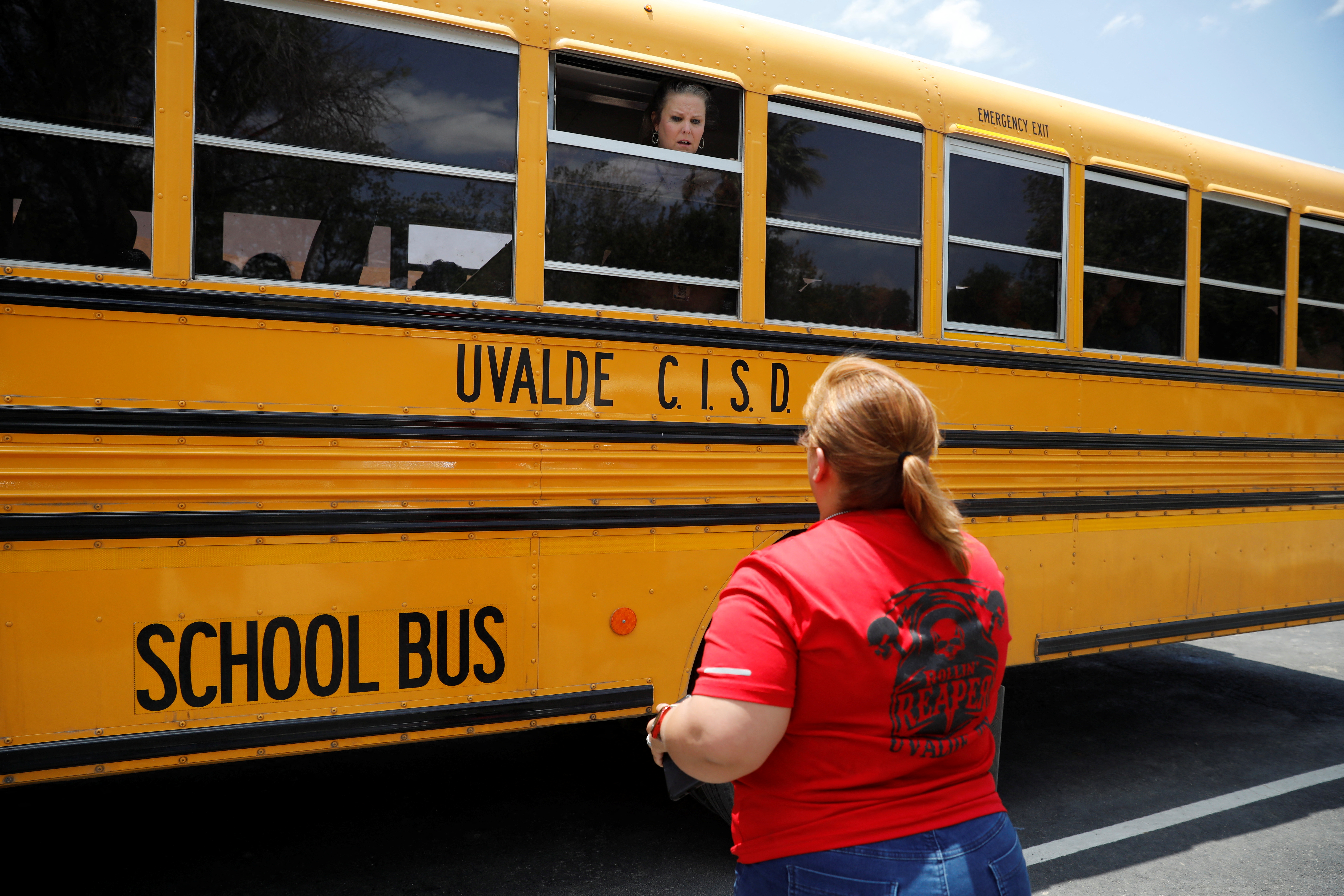 Un empleado de la escuela habla a través de la ventana de un autobús escolar con uno de los padres cerca de la escena de un presunto tiroteo (REUTERS/Marco Bello)