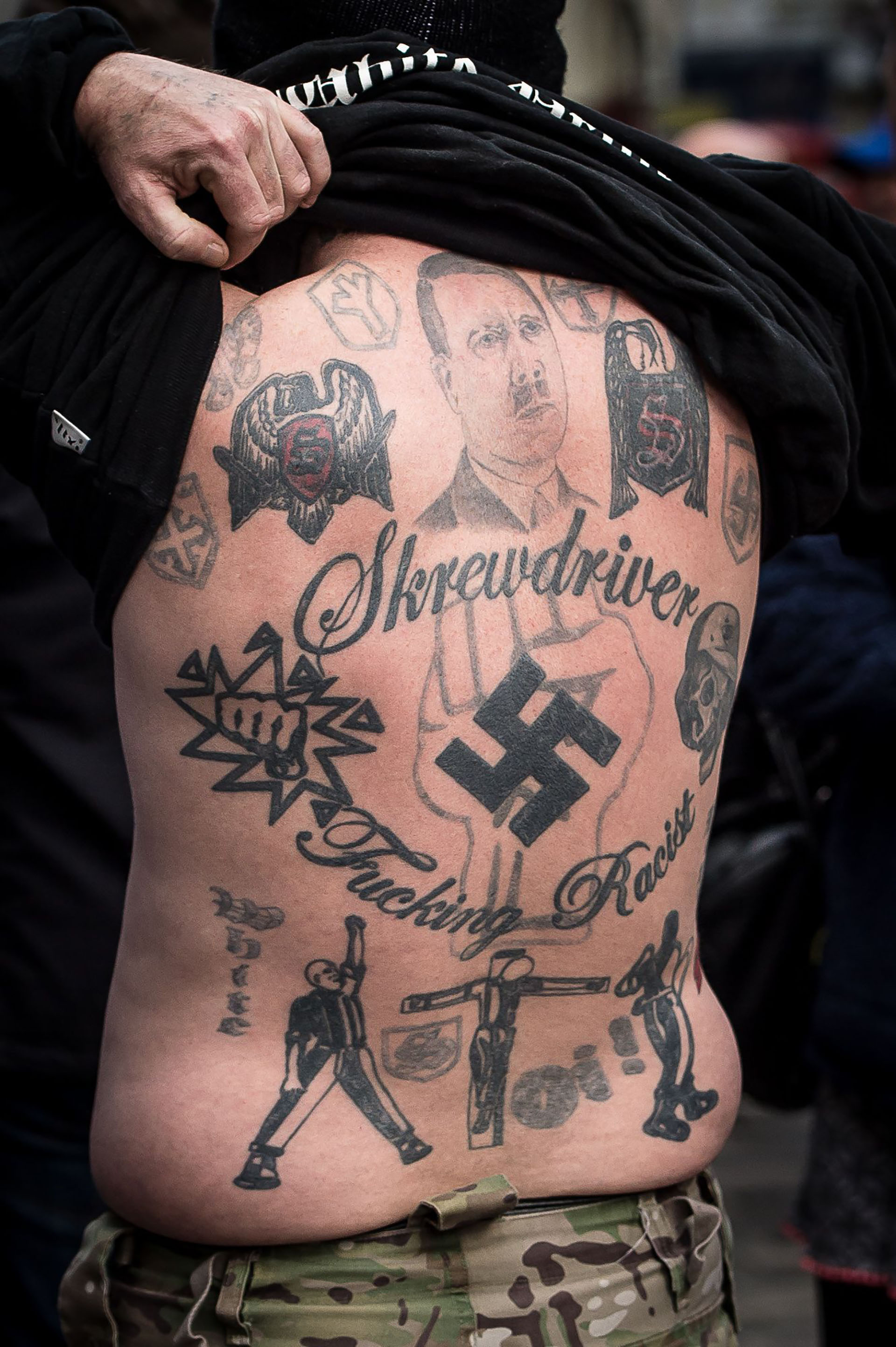 Un skinhead muestra tatuajes de Hitler, una esvástica y de Skrewdriver durante un mitin neonazi (The Grosby Group)