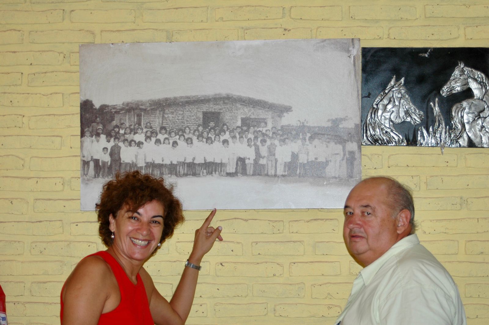 Iris junto a su querido maestro Armando Vandenberghe posan delante de una foto de ellos en la amada escuelita "rancho" de Chaco 
