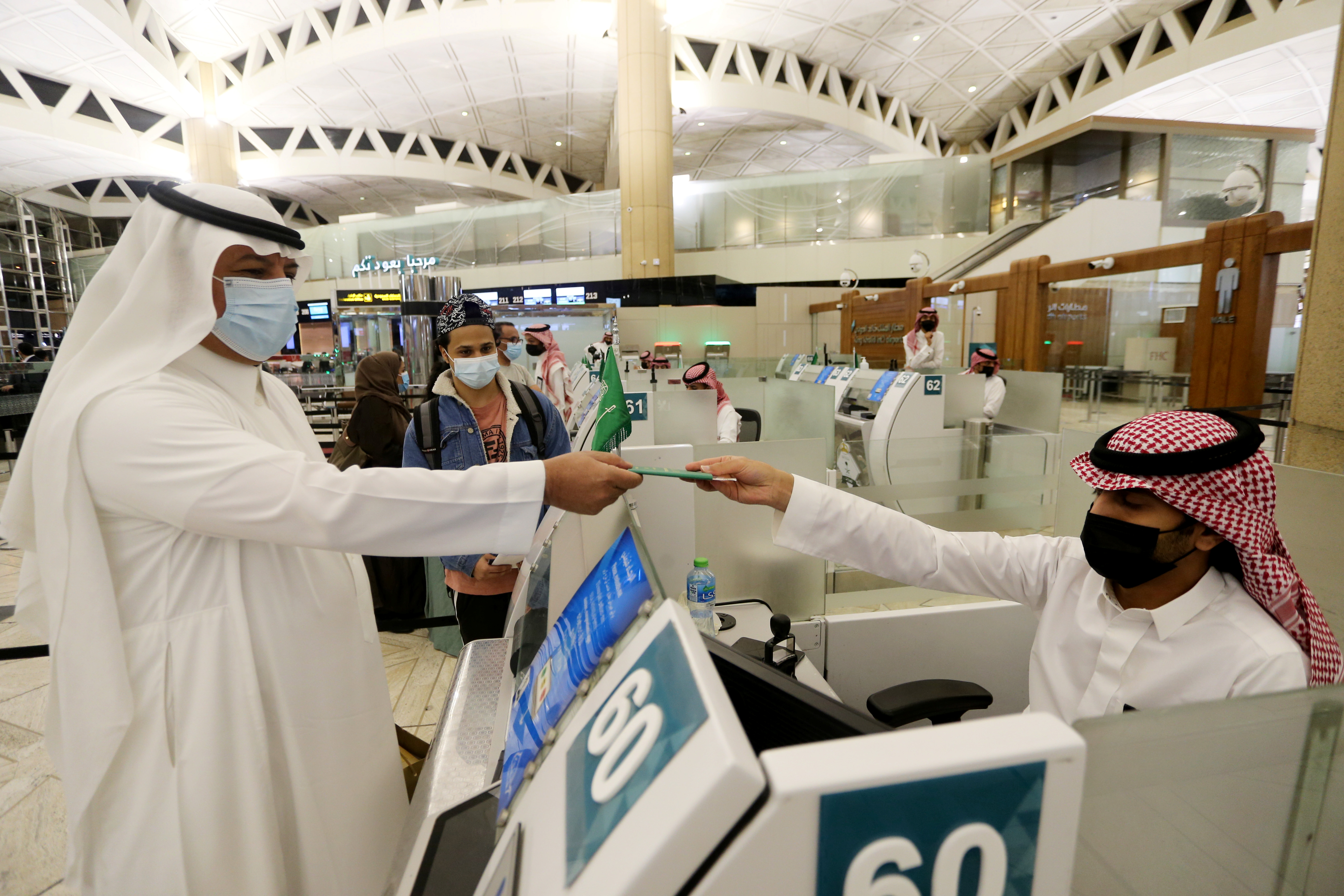 Un hombre saudí con una mascarilla obtiene su pasaporte de un oficial de inmigración saudí, en el Aeropuerto Internacional Rey Khalid, luego de que las autoridades sauditas levantaran la prohibición de viajar a sus ciudadanos después de catorce meses debido a las restricciones de la enfermedad por coronavirus (COVID-19), en Riad. Arabia Saudita
REUTERS/Ahmed Yosri