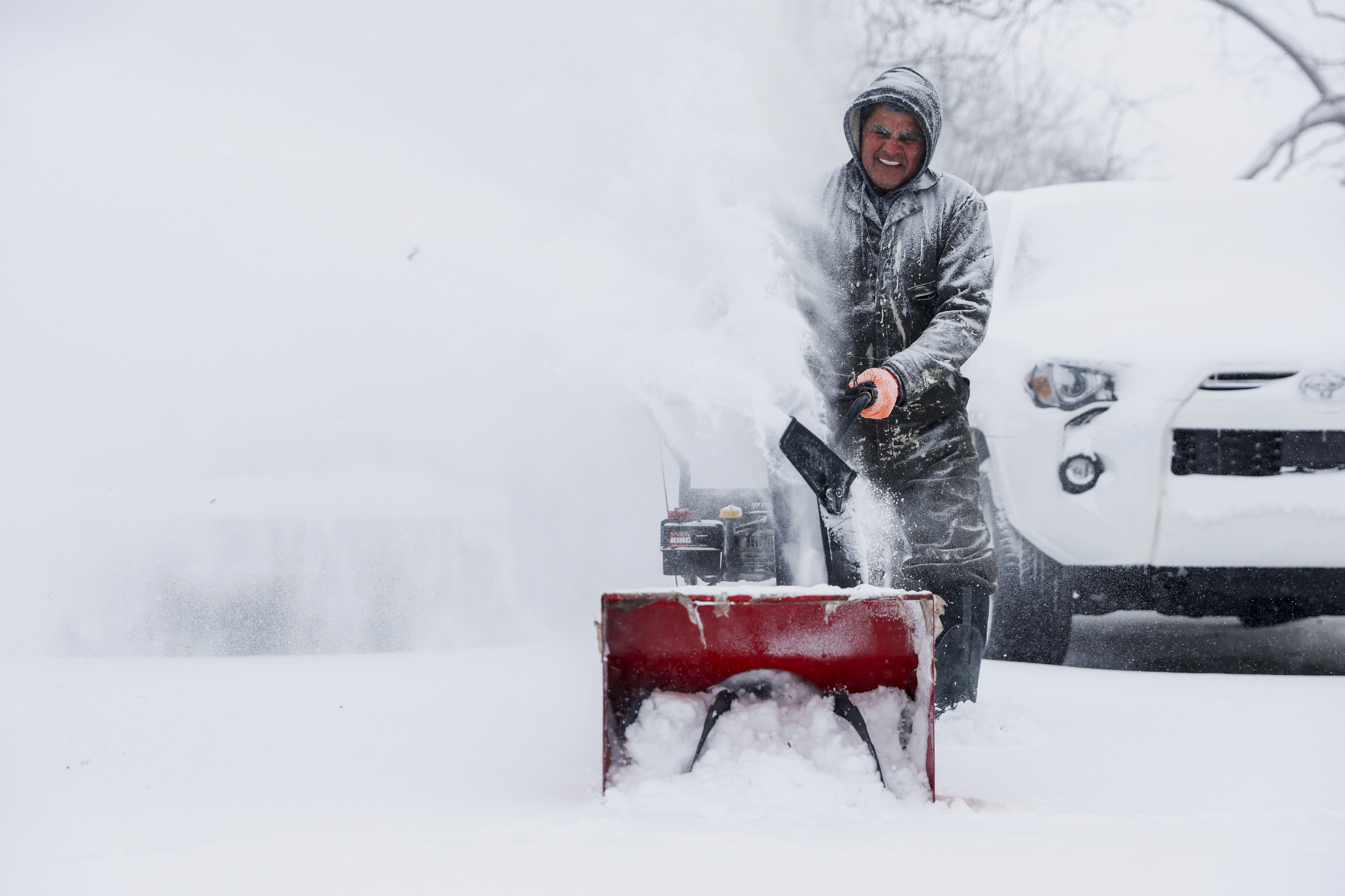 A man uses a blower to clear snow 