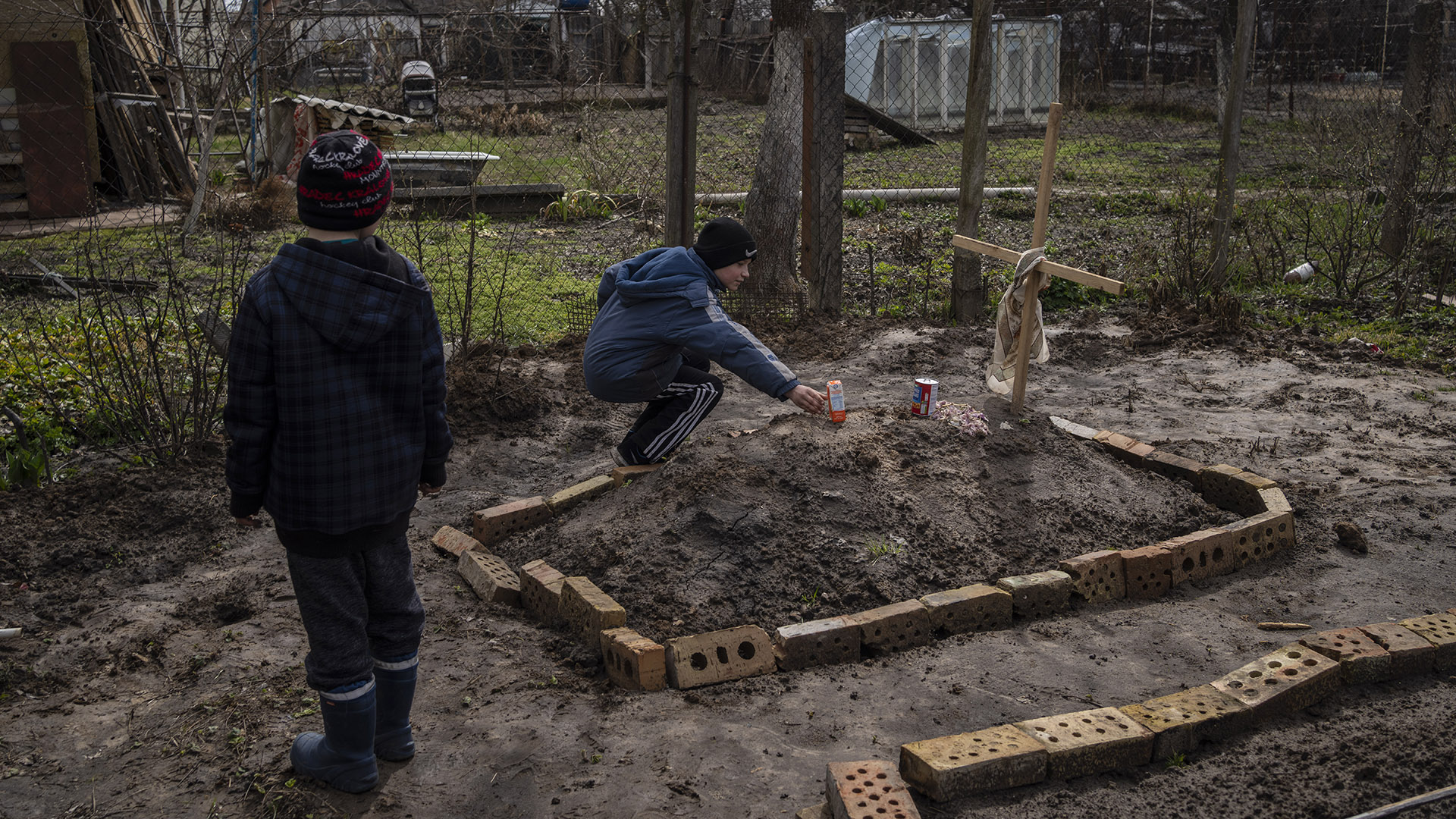 Hermano de Vlad, Vova Tanyuk, de 10 aos, coloca un jugo naranja sobre la tumba de su madre Ira (Photo AP / Rodrigo Abd)