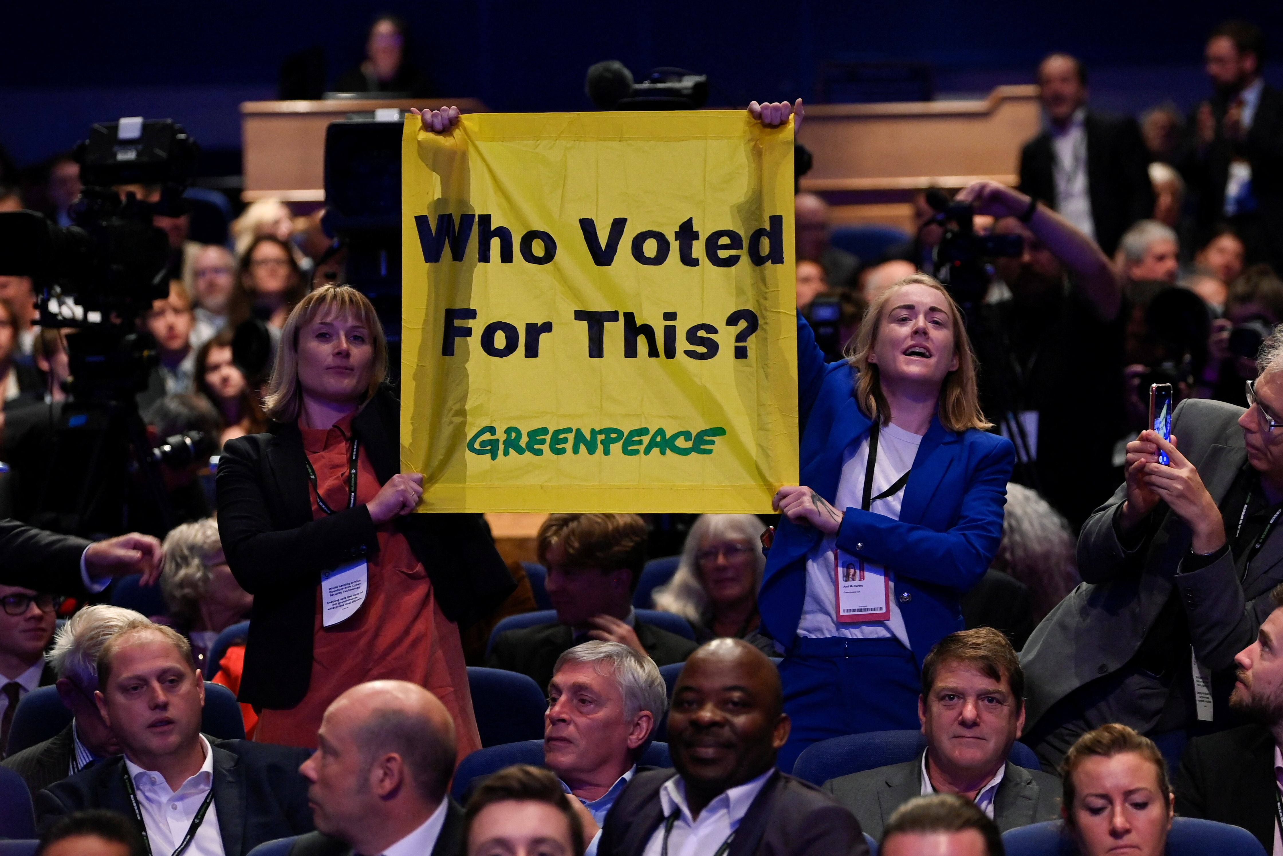 Las miembros de Greenpeace sostienen un cartel de protesta durante el discurso de la primera ministra británica Liz Truss, durante la conferencia anual del Partido Conservador de Gran Bretaña en Birmingham