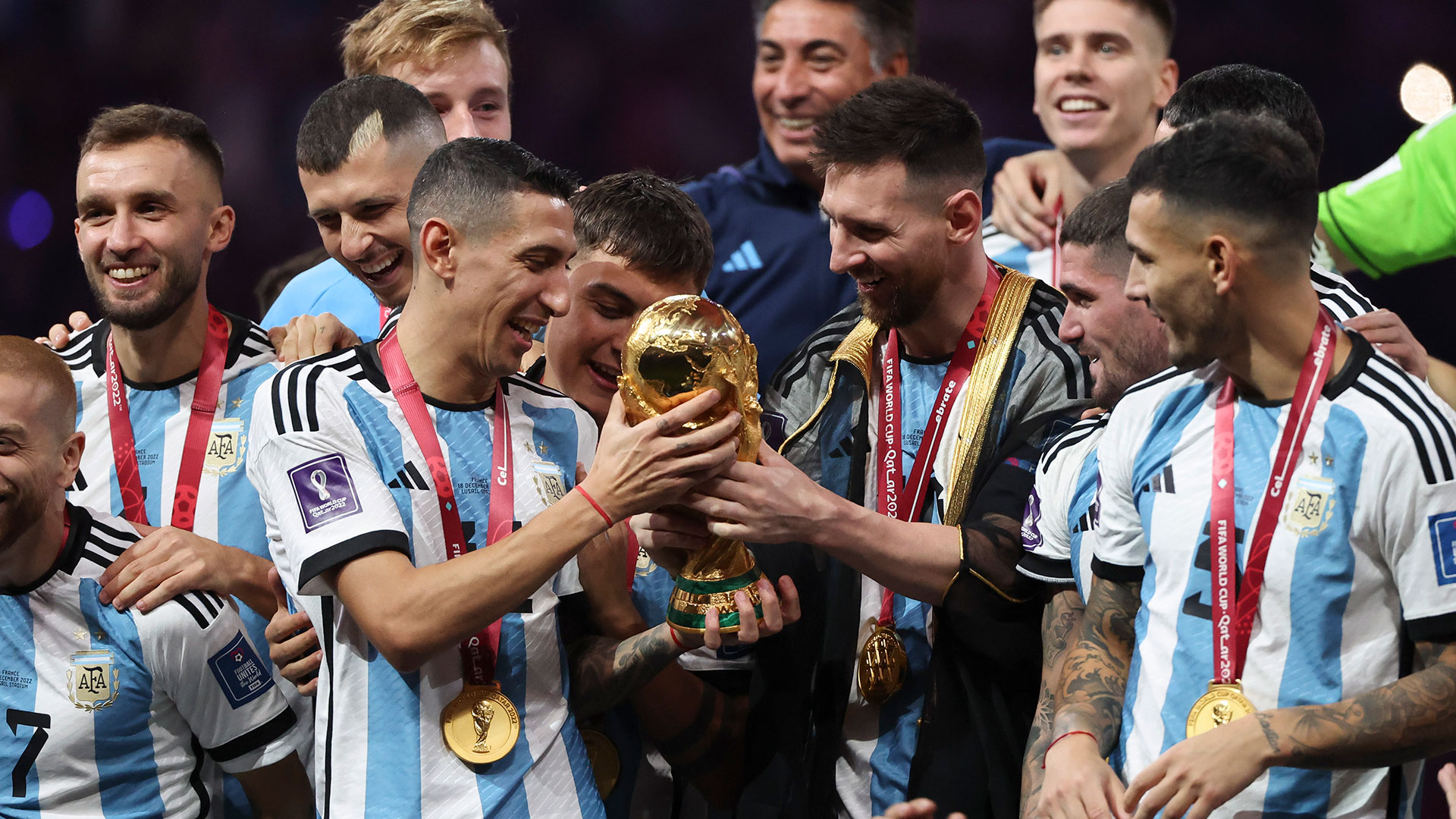 LUSAIL CITY, QATAR - DECEMBER 18: Angel Di Maria, Lionel Messi of Argentina - holding the World Cup - and teammates celebrate during the trophy ceremony following the FIFA World Cup Qatar 2022 Final match between Argentina and France at Lusail Stadium on December 18, 2022 in Lusail City, Qatar. (Photo by Jean Catuffe/Getty Images)