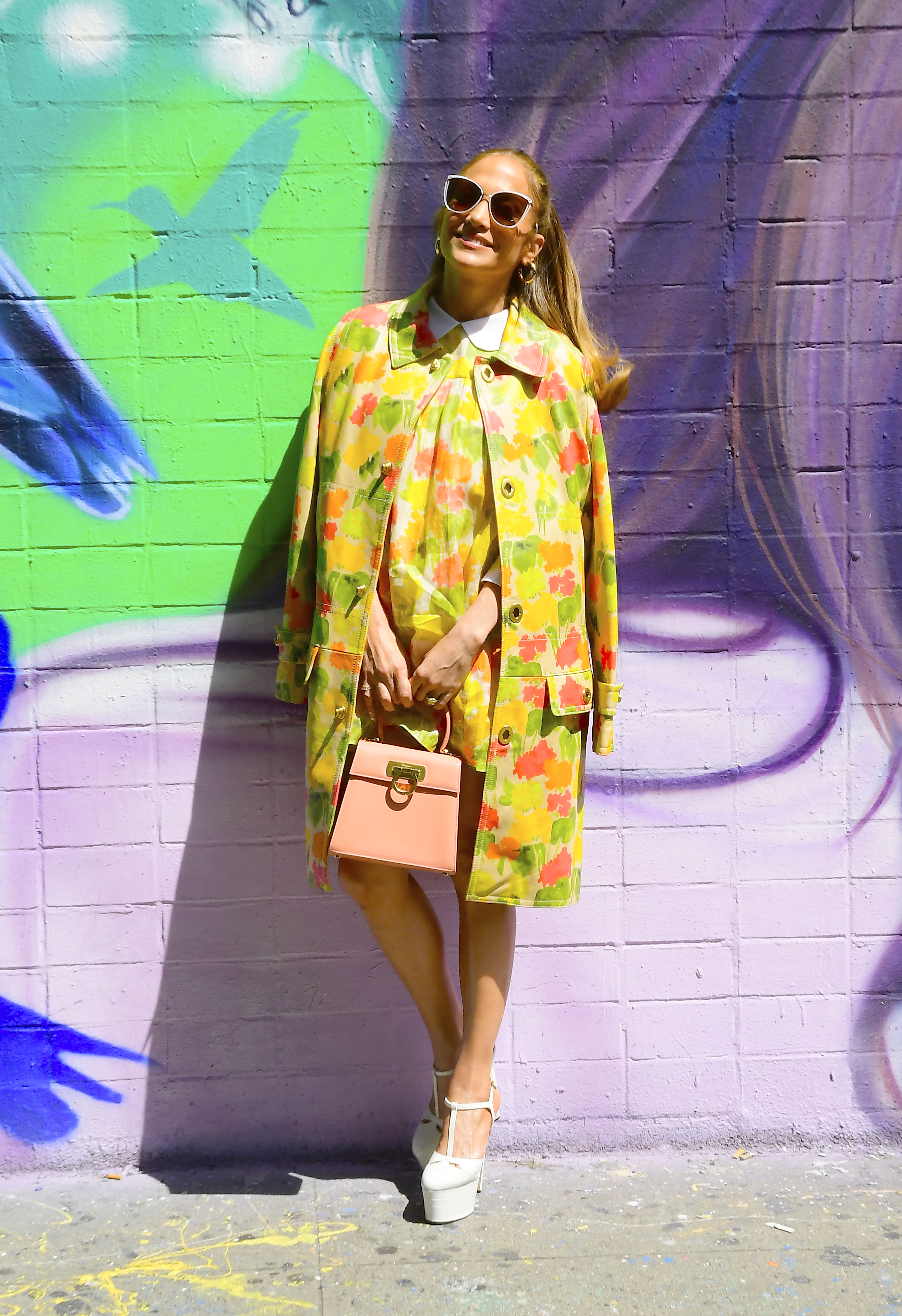 Jennifer Lopez visitó su mural en Lower East Side, Nueva York. Y lució un vestido con estampa colorida que combinó con su trench. Además, usó maxi plataformas blancas y una cartera color coral (Fotos: The Grosby Group)