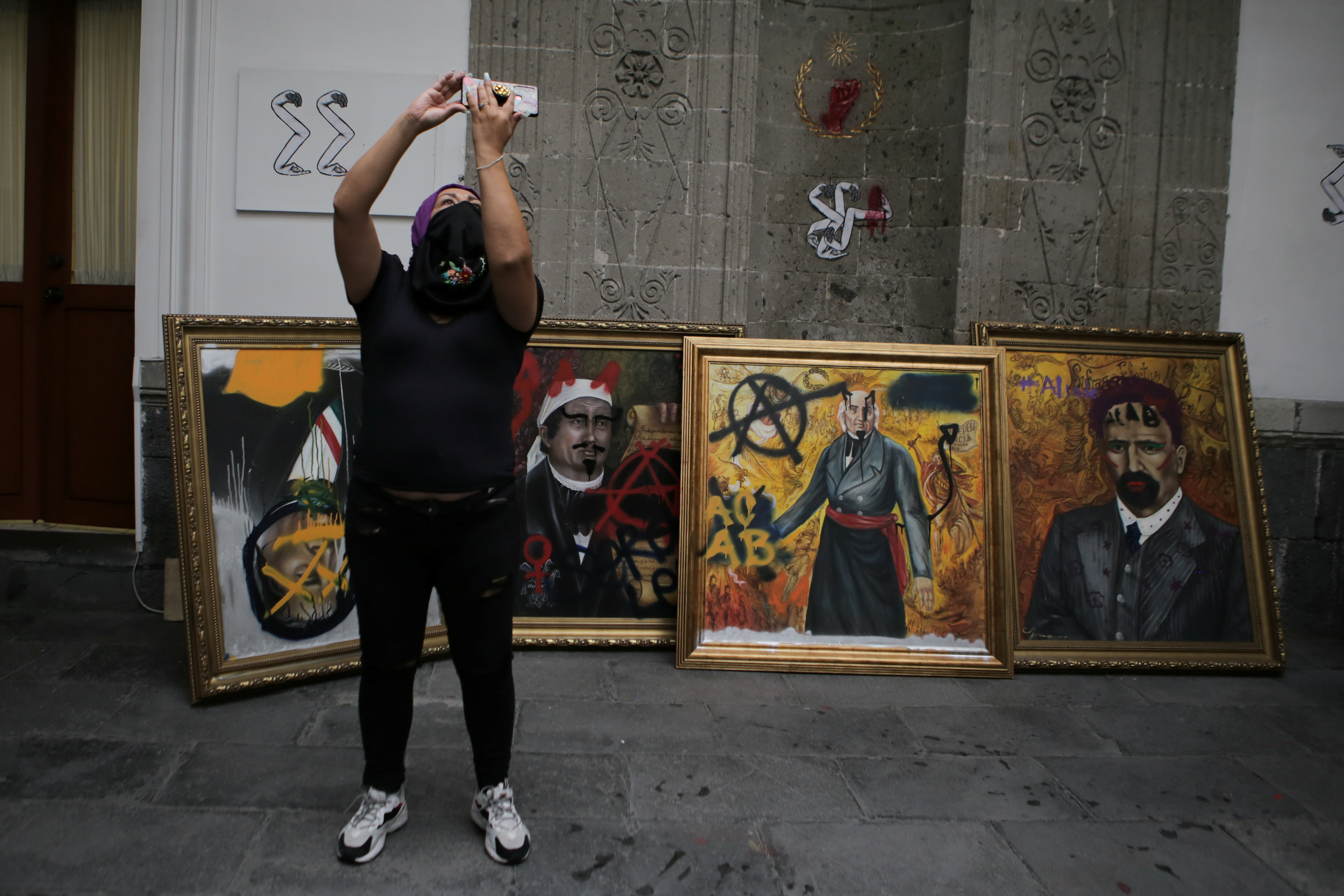 Una integrante de un colectivo feminista se toma una selfie junto a retratos vandalizados de líderes mexicanos dentro de las instalaciones del edificio de la Comisión Nacional de Derechos Humanos, en apoyo a las víctimas de violencia de género, en la Ciudad de México, México, 10 de septiembre de 2020. Fotografía tomada el 10 de septiembre de 2020.