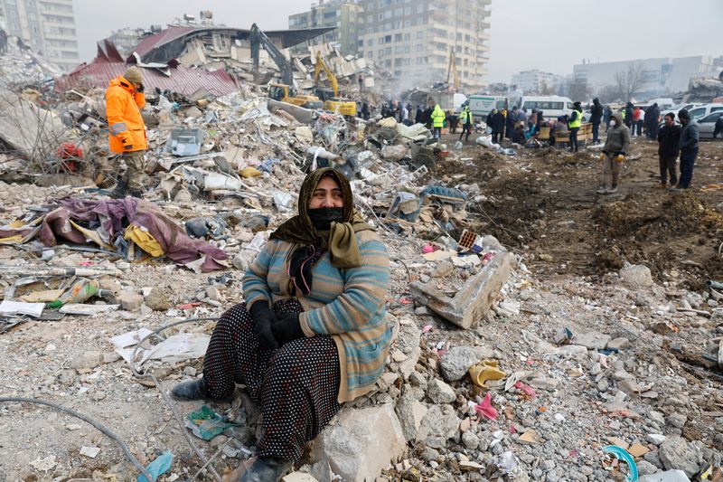 Una mujer sentada entre los escombros de un edificio derruido tras un terremoto, mientras continúan las operaciones de búsqueda de supervivientes en Kahramanmaras, Anatolia Suroriental, Turquía (Reuters)