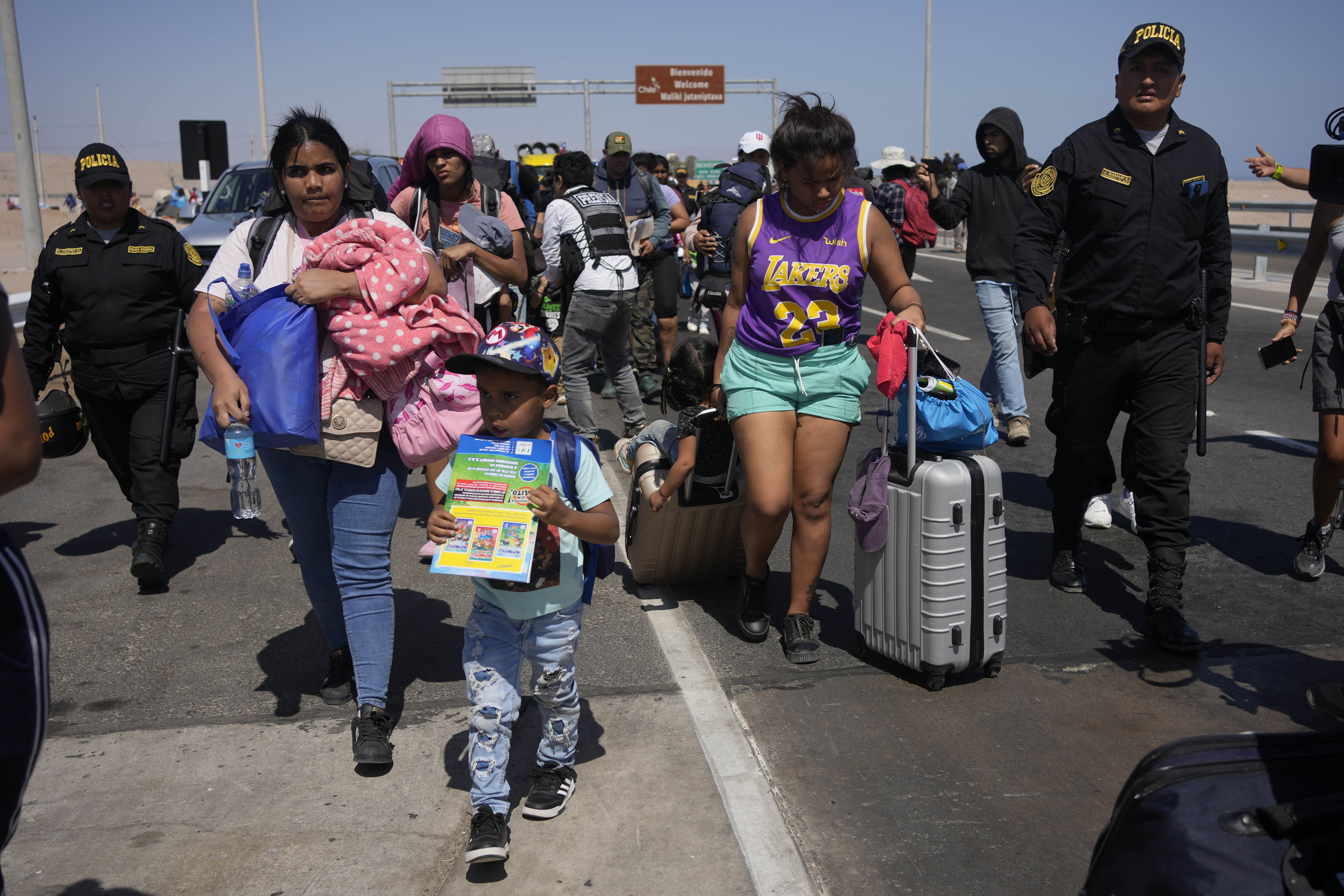 Migrantes venezolanos escoltados por la policía peruana hacia una oficina de migración en la frontera con Chile, en Tacna, Perú, el viernes 28 de abril de 2023. (AP Foto/Martín Mejía)