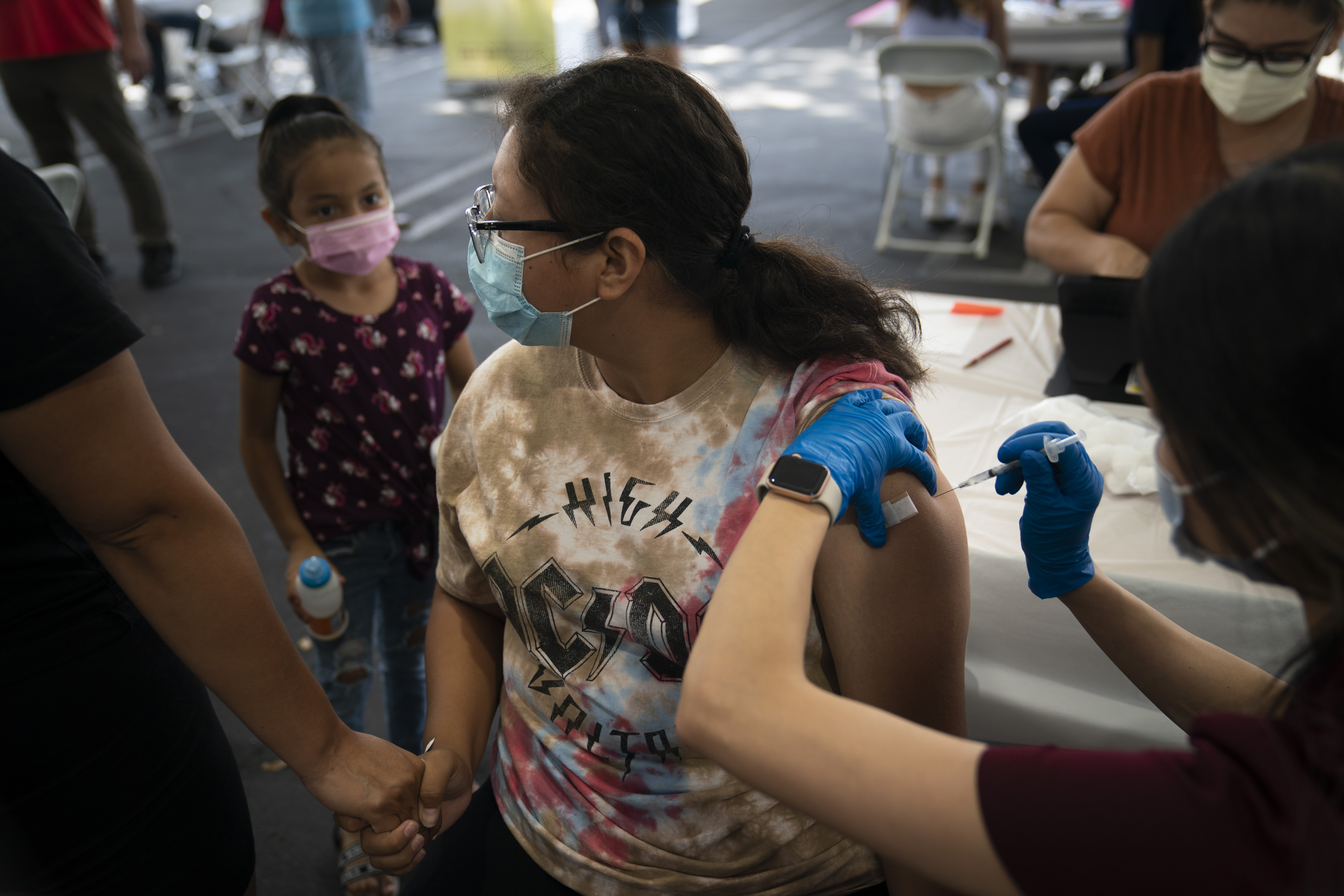 ARCHIVO - Sosteniendo la mano de su madre, Brianna Vivar, de 14 años, mira hacia otro lado mientras recibe la vacuna Pfizer COVID-19 de manos de la técnica farmacéutica Mary Tran en una clínica de vacunas instalada en el estacionamiento de CalOptima, el sábado 28 de agosto de 2021, en Orange , California (Foto AP/Jae C. Hong, Archivo)
