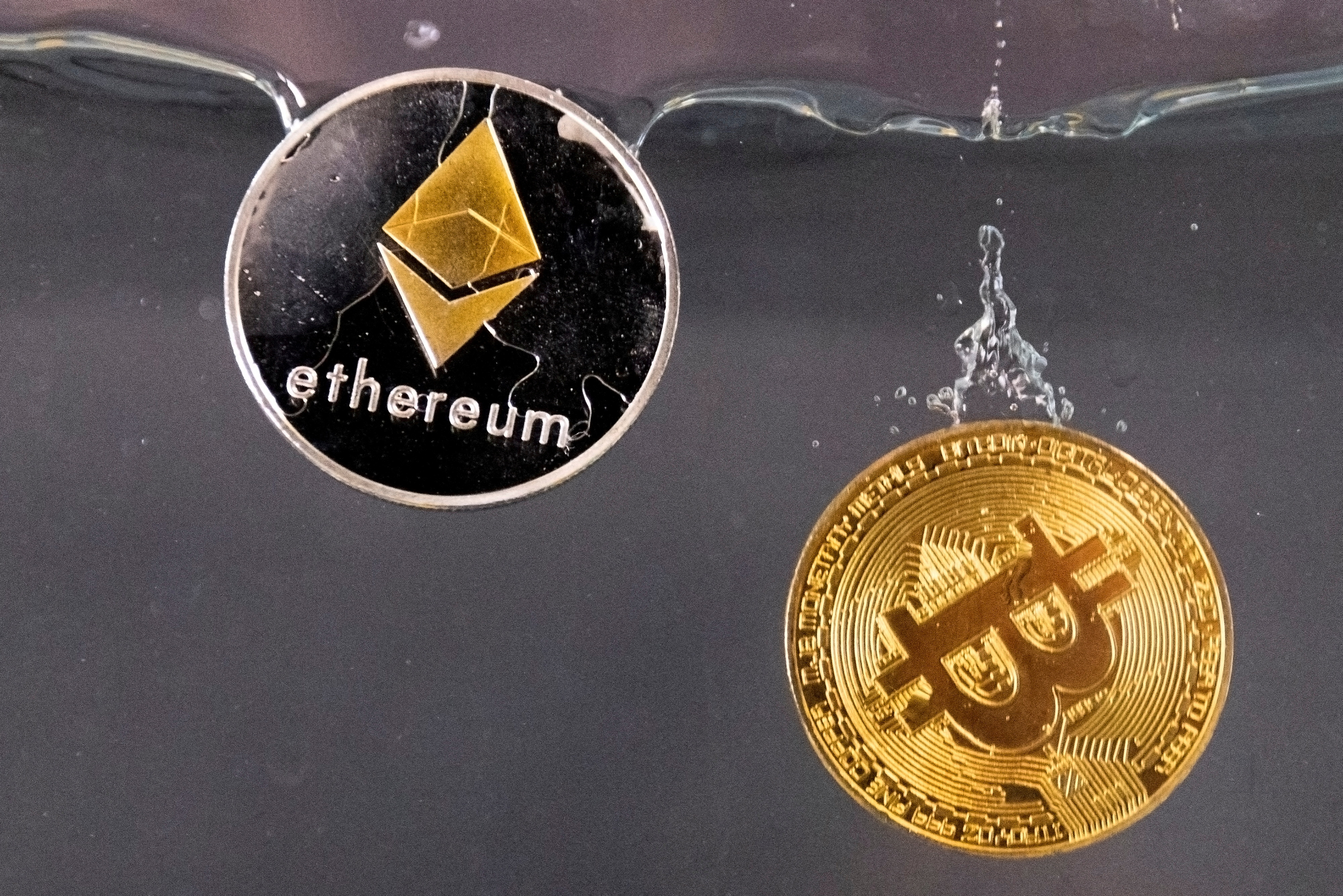 FILE PHOTO: Souvenir tokens representing cryptocurrency Bitcoin and the Ethereum network, with its native token ether, plunge into water in this illustration taken May 17, 2022. REUTERS/Dado Ruvic/File Photo