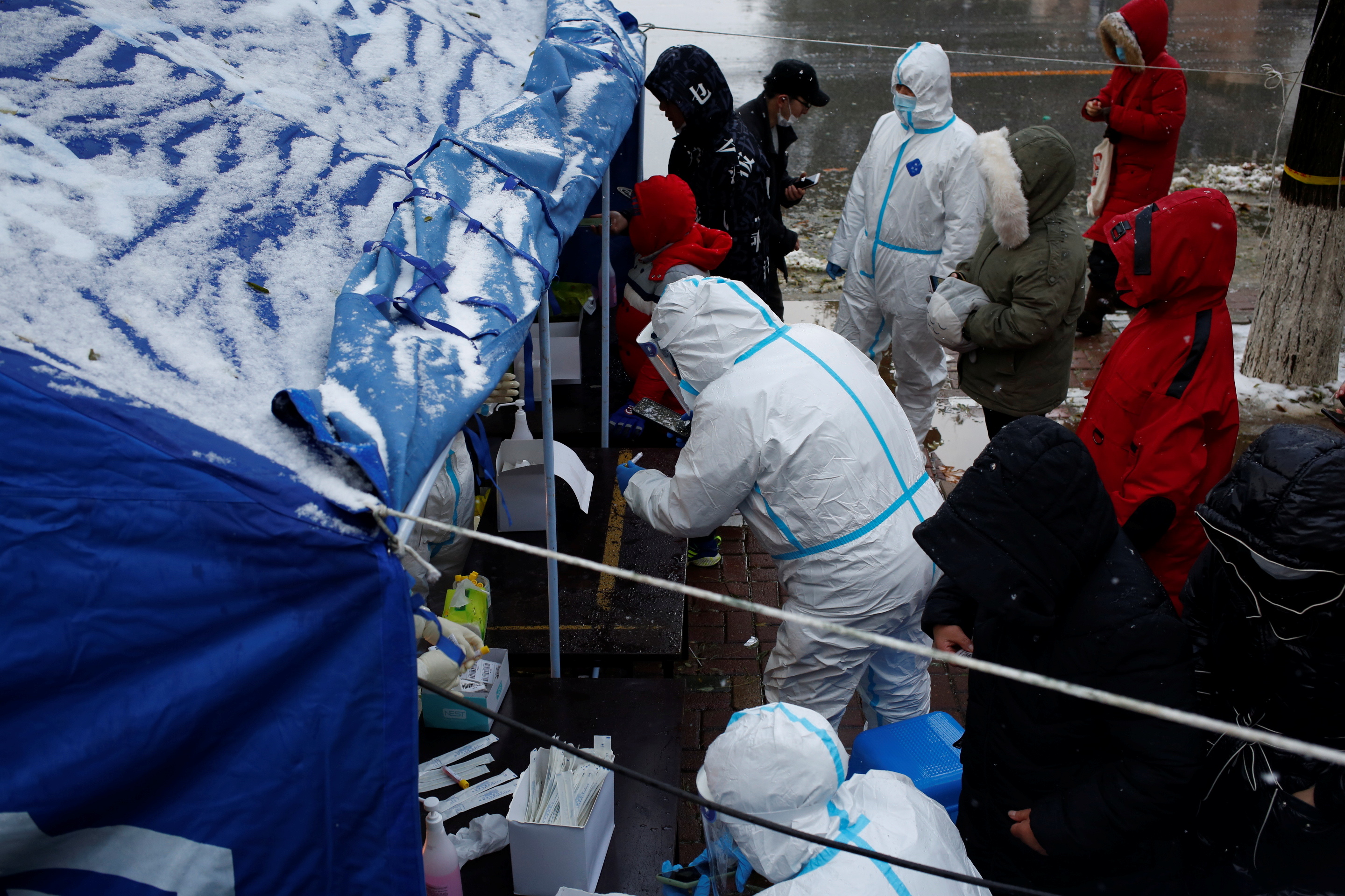 La gente hace cola para las pruebas de ácido nucleico en la nieve en un sitio de pruebas en Jinpu New Area, tras los casos de la enfermedad del coronavirus (COVID-19) en Dalian, provincia de Liaoning, China 8 de noviembre de 2021. Fotografía tomada el 8 de noviembre de 2021. cnsphoto via REUTERS/Archivo