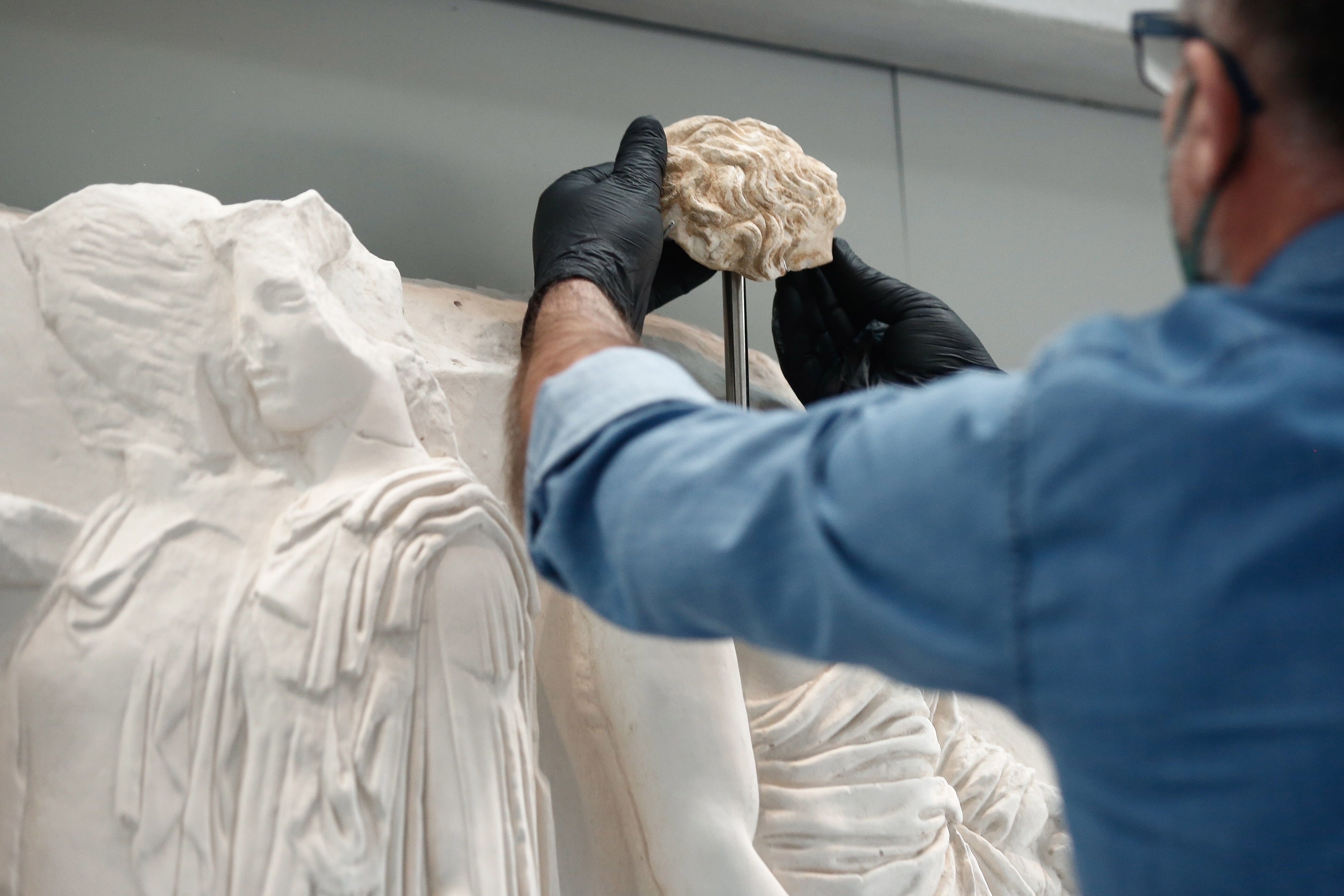 Un empleado del Museo de la Acrópolis coloca un fragmento en una parte del friso del Partenón (EFE/EPA/YANNIS KOLESIDIS)