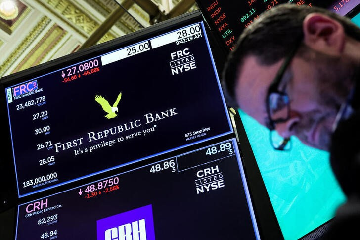 Un operador mira unas cotizaciones junto a una pantalla con información sobre First Republic Bank en la Bolsa de Nueva York, EEUU. 13 marzo 2023. REUTERS/Brendan McDermid