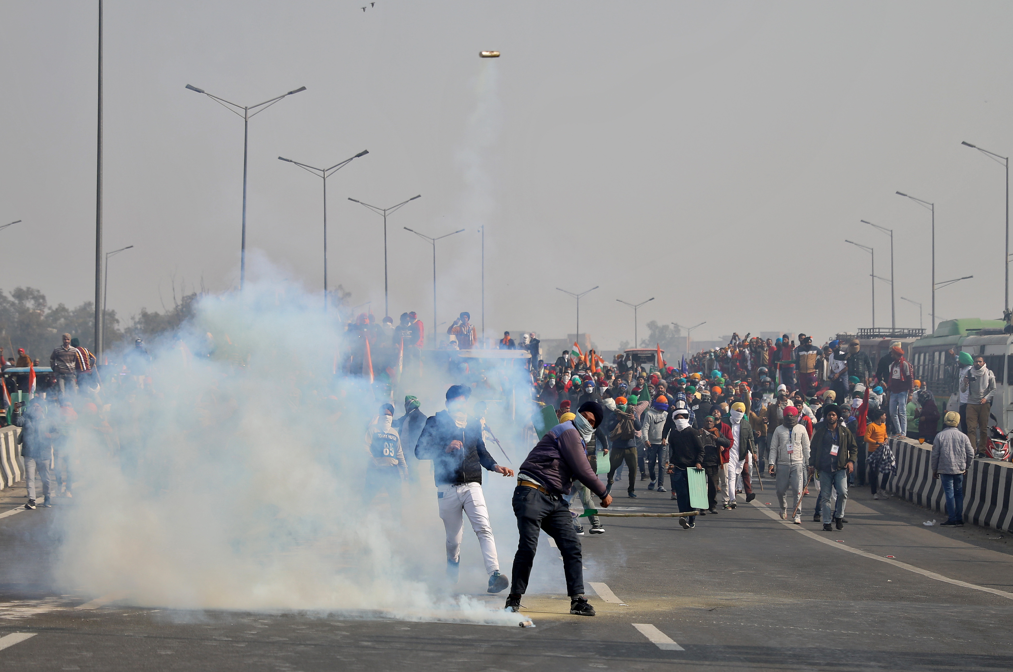 Un hombre devuelve una lata de gas lacrimógeno a la policía en la frontera de Ghazipur, cerca de Delhi (REUTERS/Stringer)