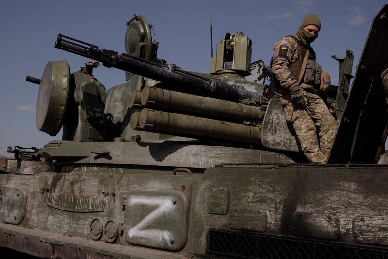 A Ukrainian soldier sitting on a captured Russian armored vehicle marked with the symbol "FROM"used by Russian forces during their invasion of Ukraine, outside kyiv, Ukraine, March 29, 2022. REUTERS/Thomas Peter