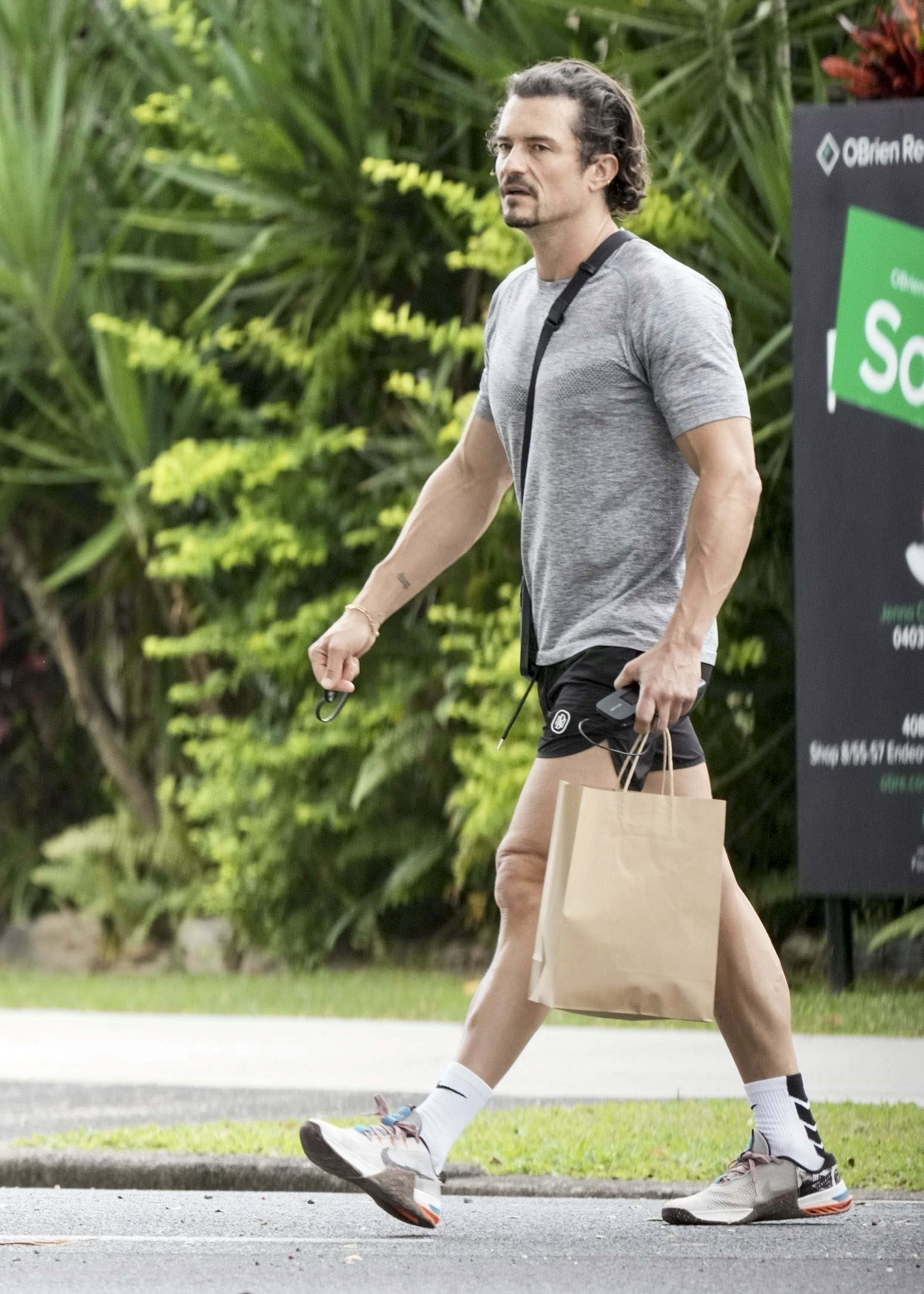Orlando Bloom toured a market in Port Douglas, Australia, after training in a private gym.  He wore a sporty look with black shorts and a gray shirt.