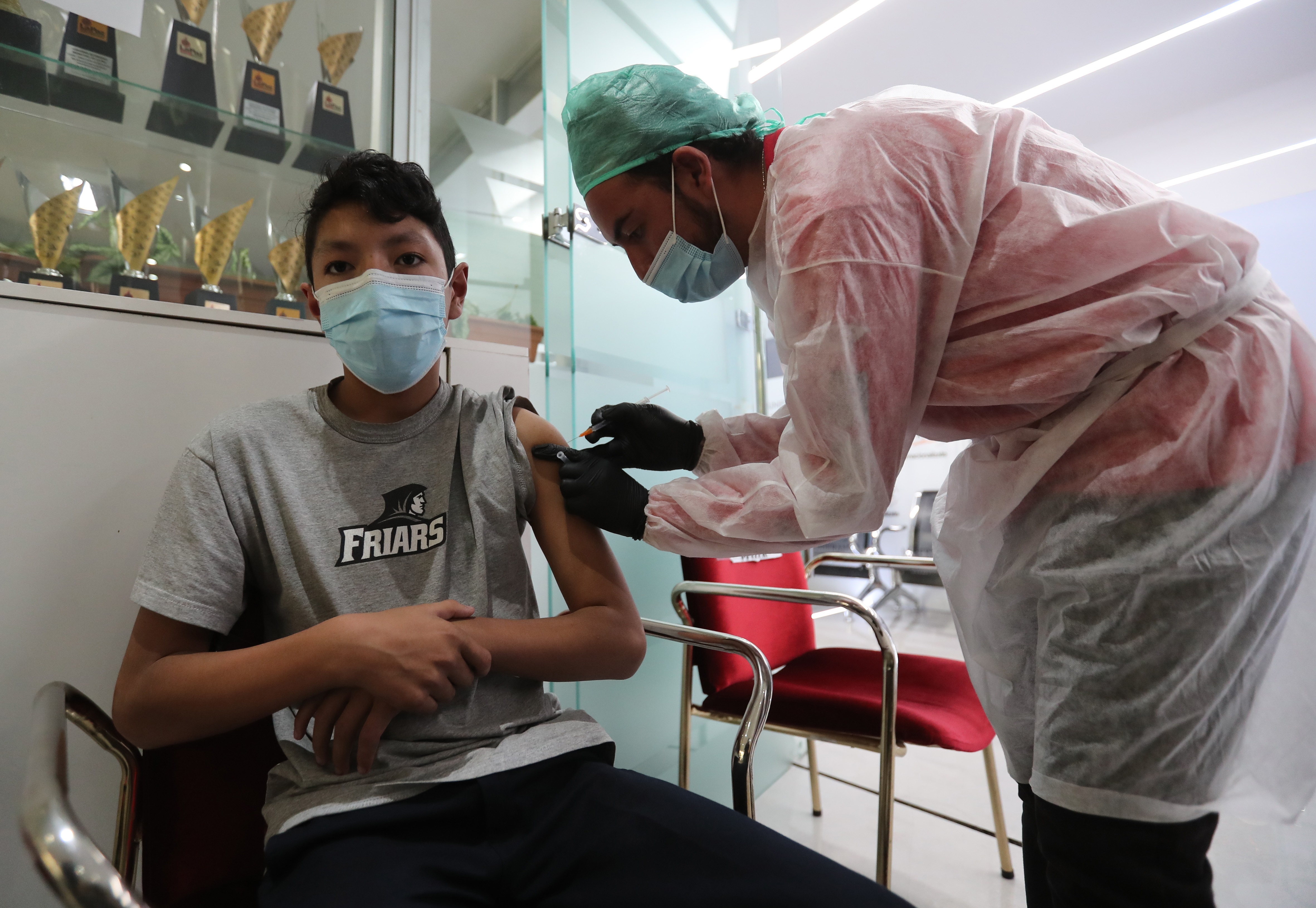 Un funcionario de salud coloca una vacuna a un menor de edad