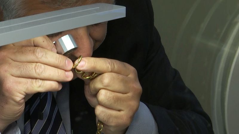 Un empleado de una casa de empeño examina piezas de oro que van a ser vendida (Reuters) 