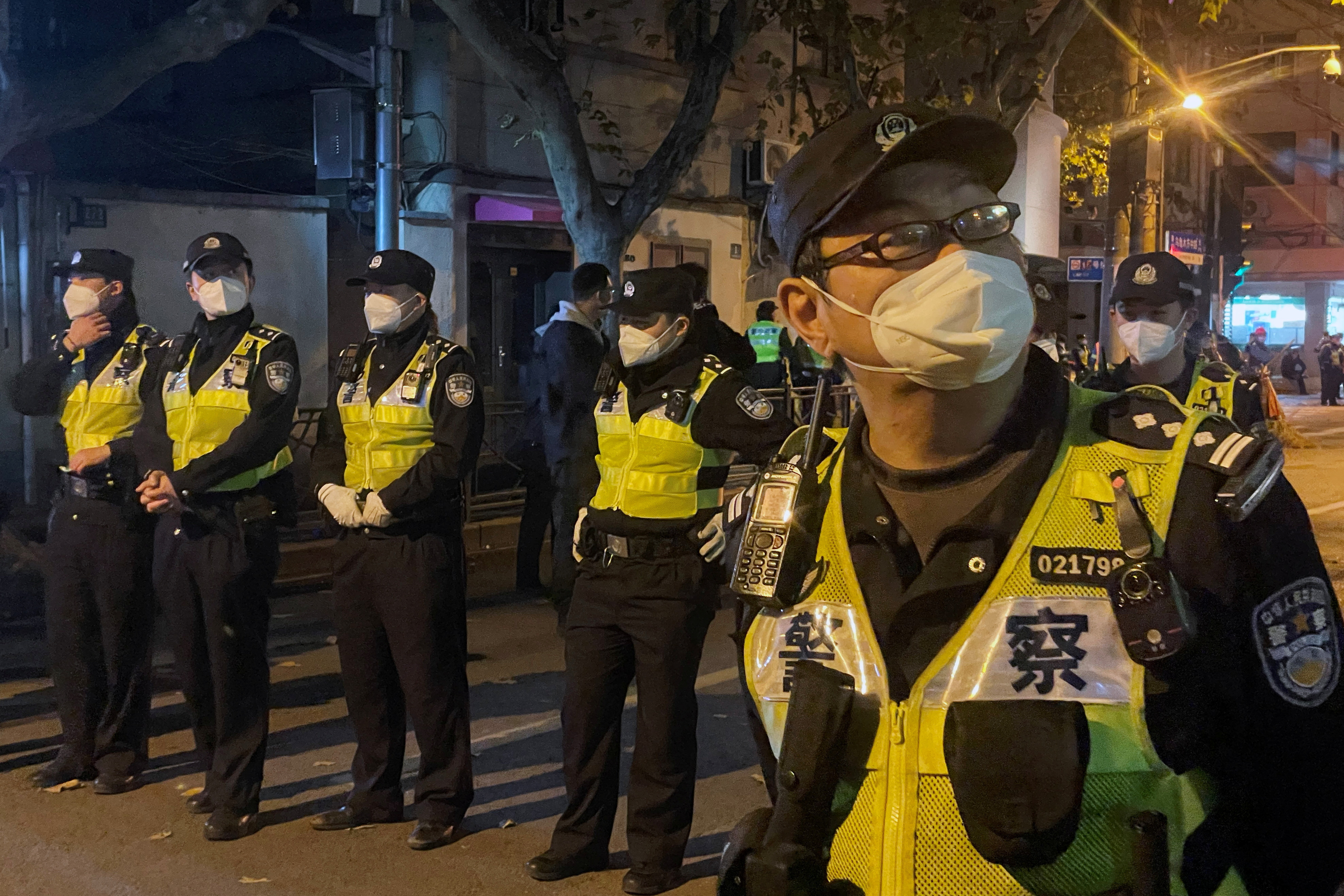 Petugas polisi berjaga selama demonstrasi menentang pembatasan COVID-19 setelah kebakaran mematikan di Urumqi, di Shanghai (REUTERS / Casey Hall)