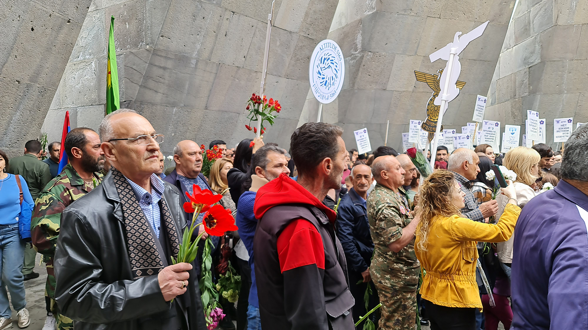 Hombres, mujeres y militares llevan flores para depositor alrededor de la "llama eterna"