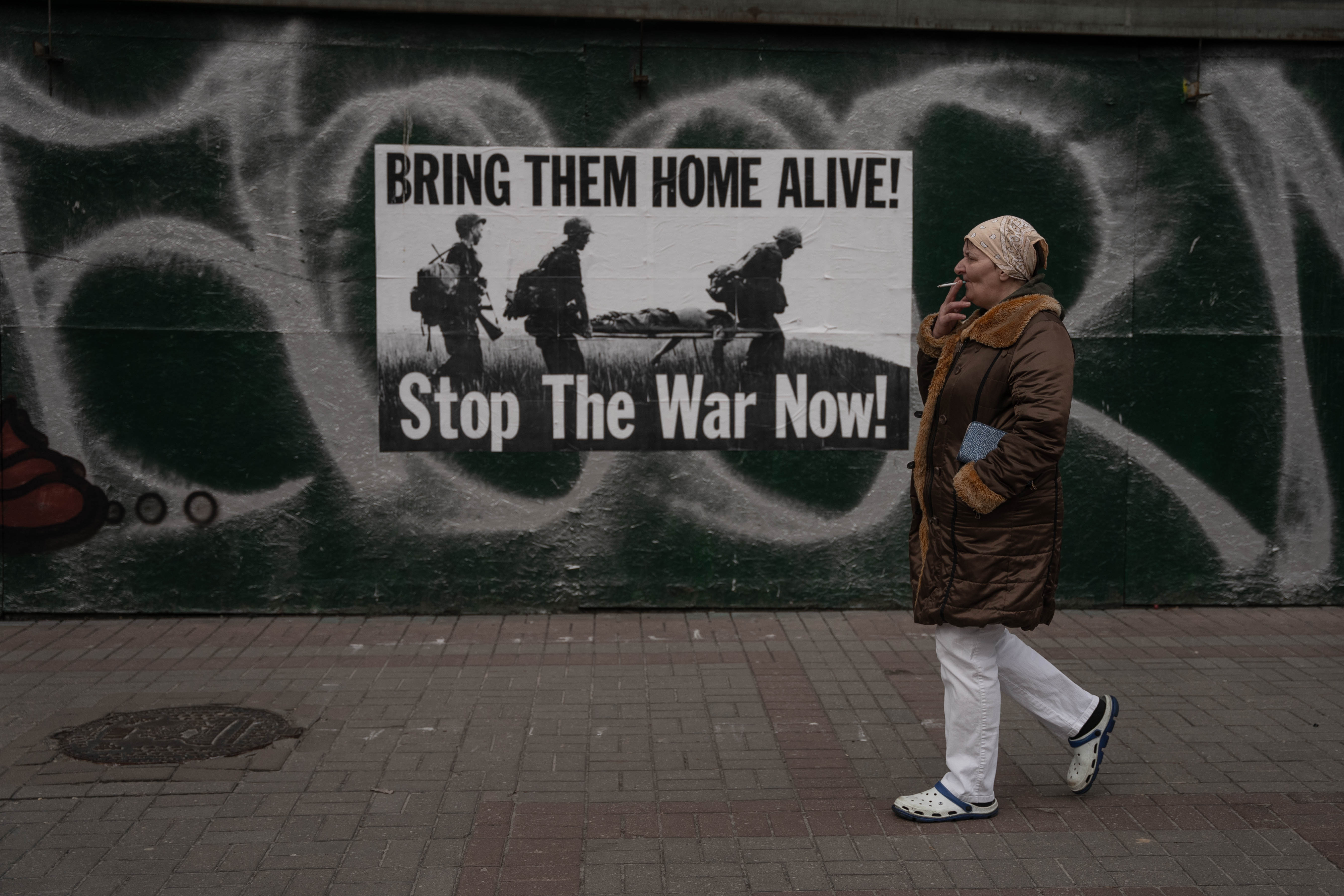 Una mujer camina frente a un cartel pidiendo el fin de la guerra en la ciudad de Kyiv.