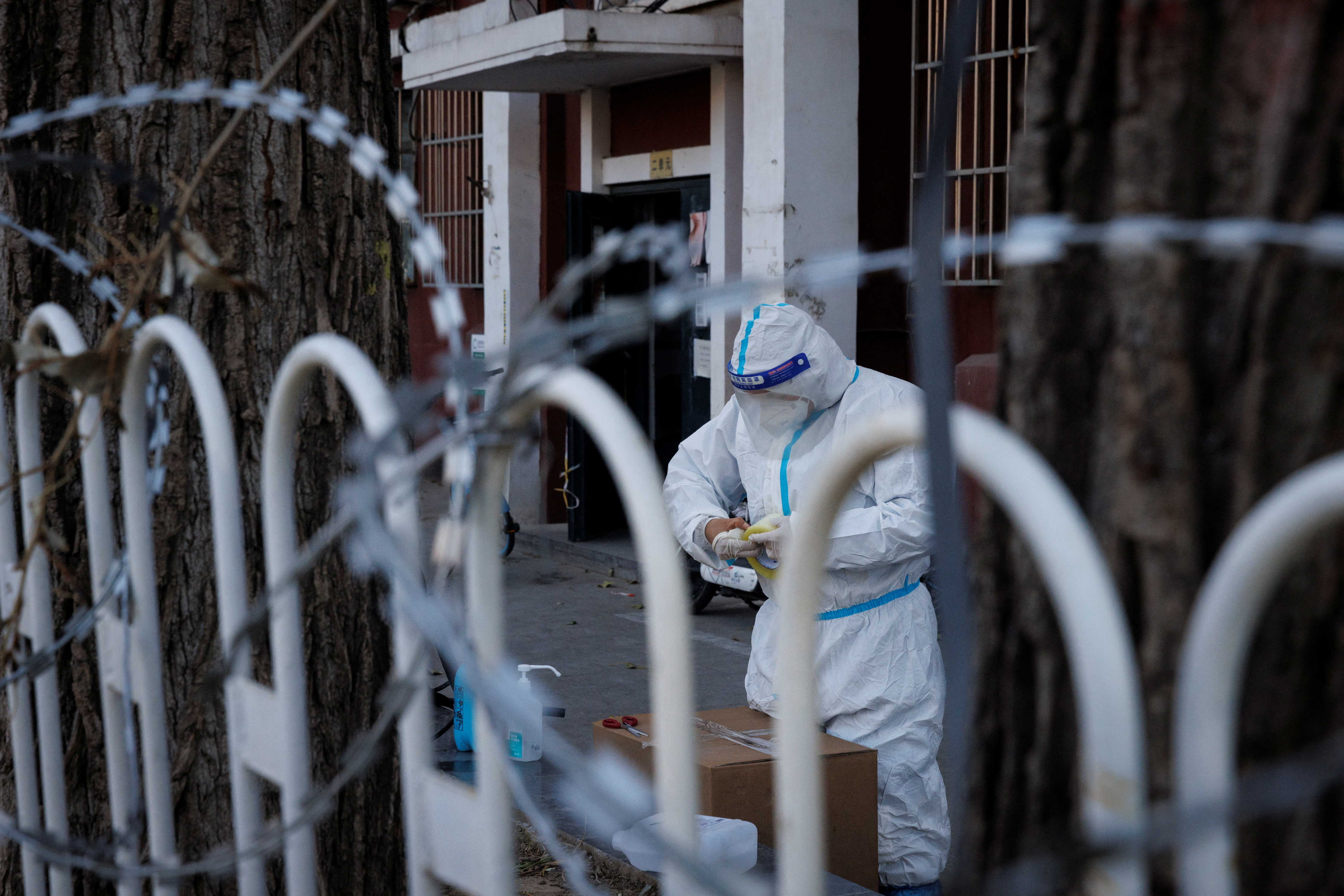Un trabajador de control pandémico con traje protector trabaja en un complejo residencial parcialmente cerrado mientras continúan los brotes de la enfermedad coronavirus (COVID-19) en Beijing, China, 30 de noviembre de 2022. REUTERS/Thomas Peter
