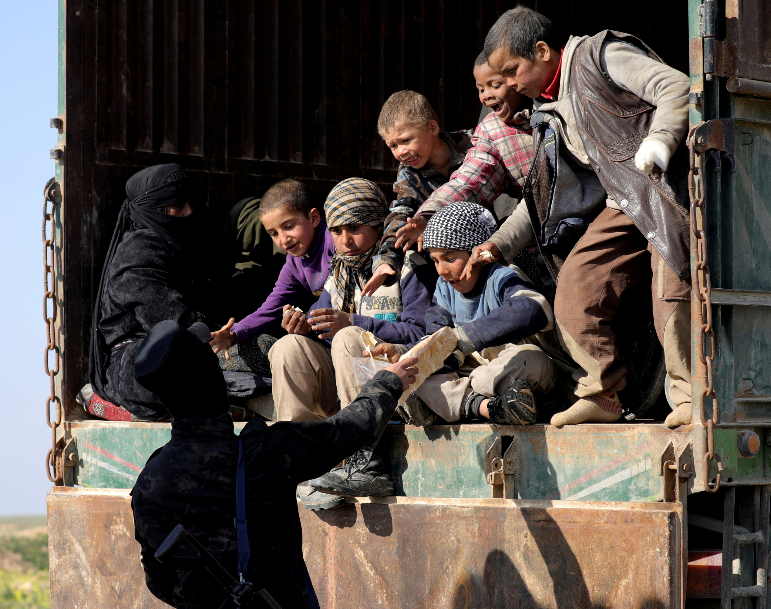Un miliciano de las Fuerzas Democráticas Kurdas entrega pan a unos niños en Baghouz, Deir Al Zor (REUTERS/Rodi Said/Archivo)