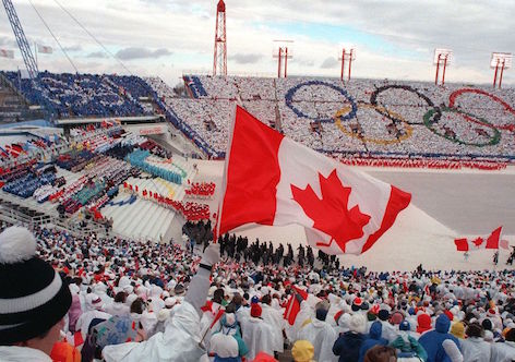Fans cheer and wave flags as the Canadian delegation (lower right) parades during the opening ceremony of the XVth Winter Olympic Games 13 February 1988 in Calgary.  AFP PHOTO/JONATHAN UTZ (Photo credit should read JONATHAN UTZ/AFP/Getty Images)