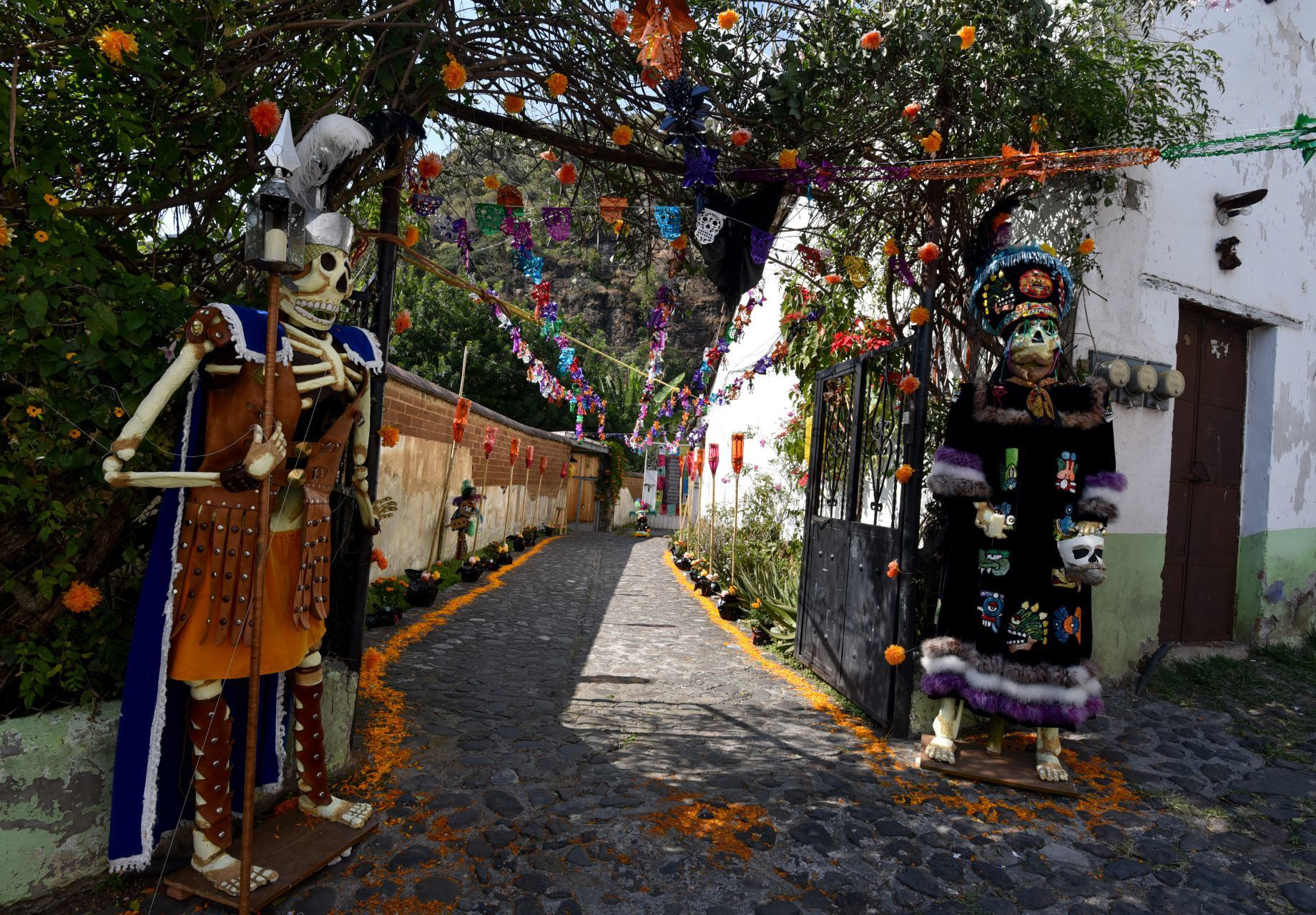 Malinalco, Estado de México, México. 1 de noviembre de 2020. La tradición del Día de muertos en Malinalco se vive en su máximo esplendor este 1 y 2 de noviembre al instalarse las ofrendas para los Muertos Nuevos, en esta ocasión fueron 68 ofrendas las instaladas en donde se representa la vida y gustos de la persona que partió en el último año, las familias llegan a tardar más de un mes para poder armar estas ofrendas; las puertas de cada hogar se abren para todo aquel que quiera visitarlos, llevando una cera para iluminar el camino de los Muertos y recibiendo algún presente por parte de los familiares, elementos como la flor de cempasúchil, incienso, velas, fruta, pan, dulces, comida, bebida, no pueden faltar, acompañado de la representación de lo que le gustaba hacer en vida al nuevo muerto.
