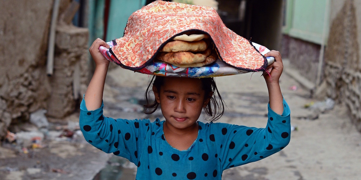 Una niña afgana lleva una canasta de pan en la cabeza en la parte antigua de Kabul el 2 de septiembre de 2014. La economía de Afganistán ha mejorado significativamente desde la caída del régimen talibán en 2001, en gran parte debido a la infusión de asistencia internacional. A pesar de la mejora significativa en la última década, el país sigue siendo extremadamente pobre y sigue dependiendo en gran medida de la ayuda exterior. (WAKIL KOHSAR / AFP / Getty Images)