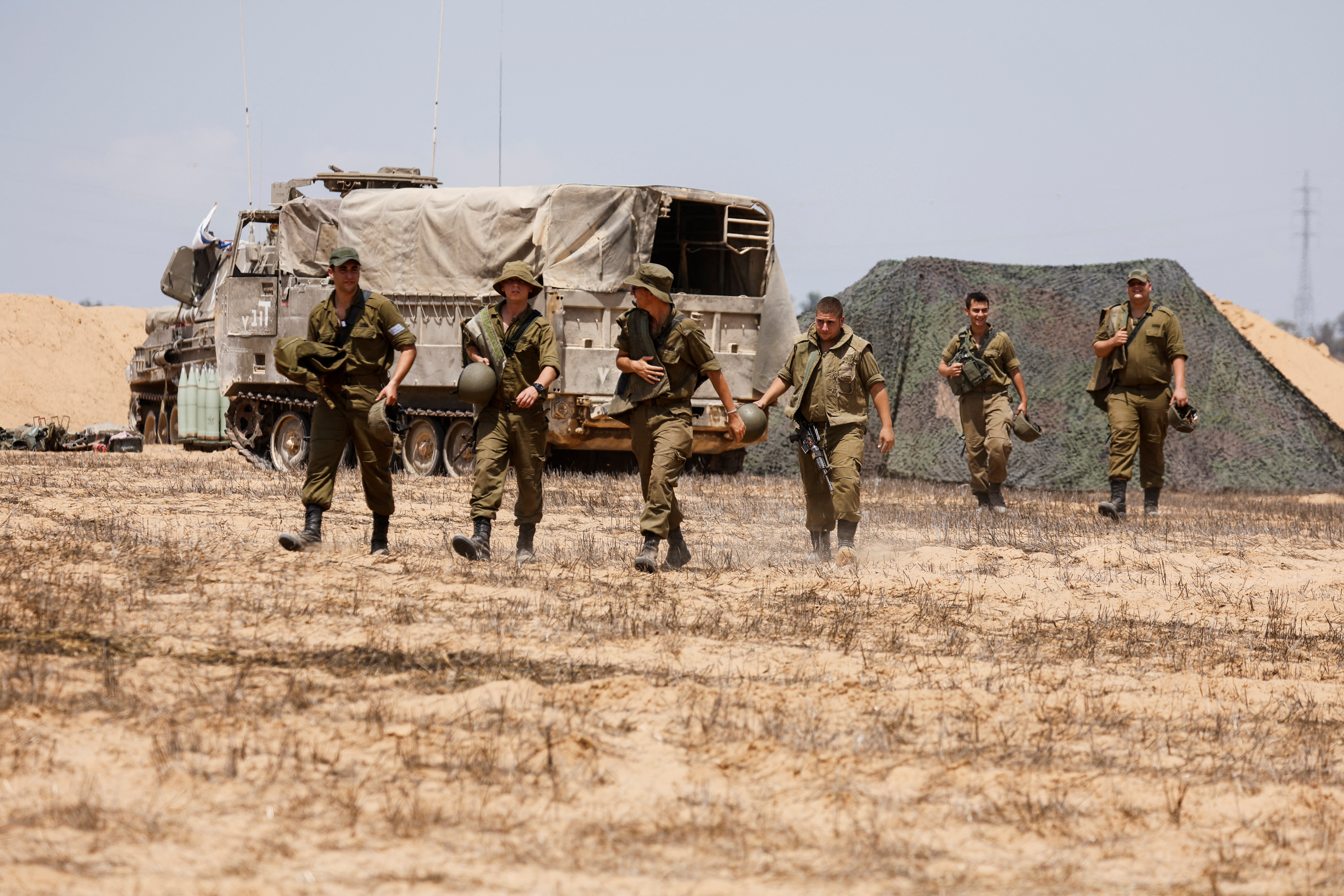 Soldados israelíes caminan junto a una unidad de artillería móvil en un campo en el lado israelí de la frontera con la Franja de Gaza el 6 de agosto de 2022. REUTERS/Amir Cohen