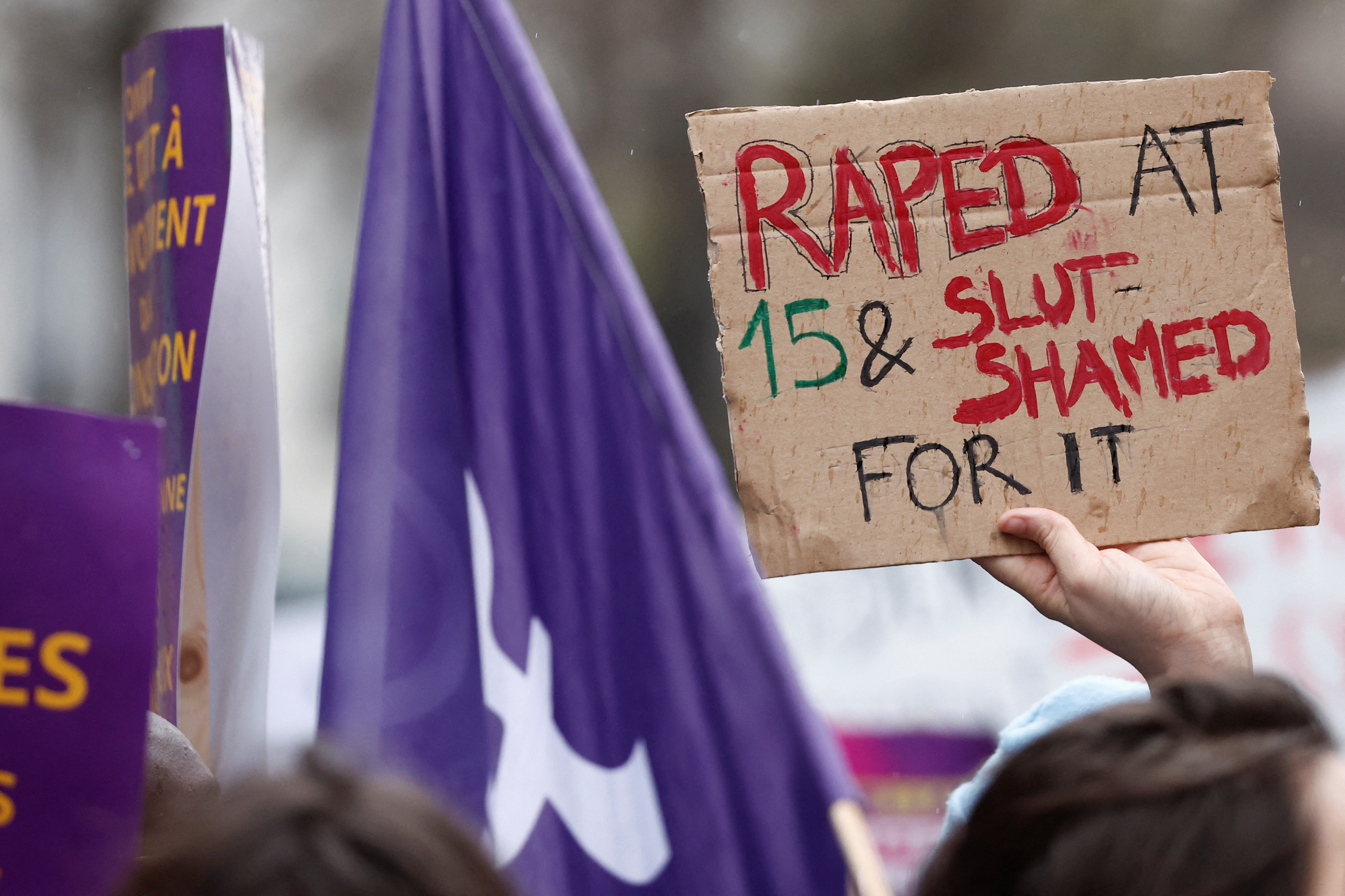 Una mujer muestra un cartel que dice "Violada a los 15 y tildada de puta por ello", en Francia.