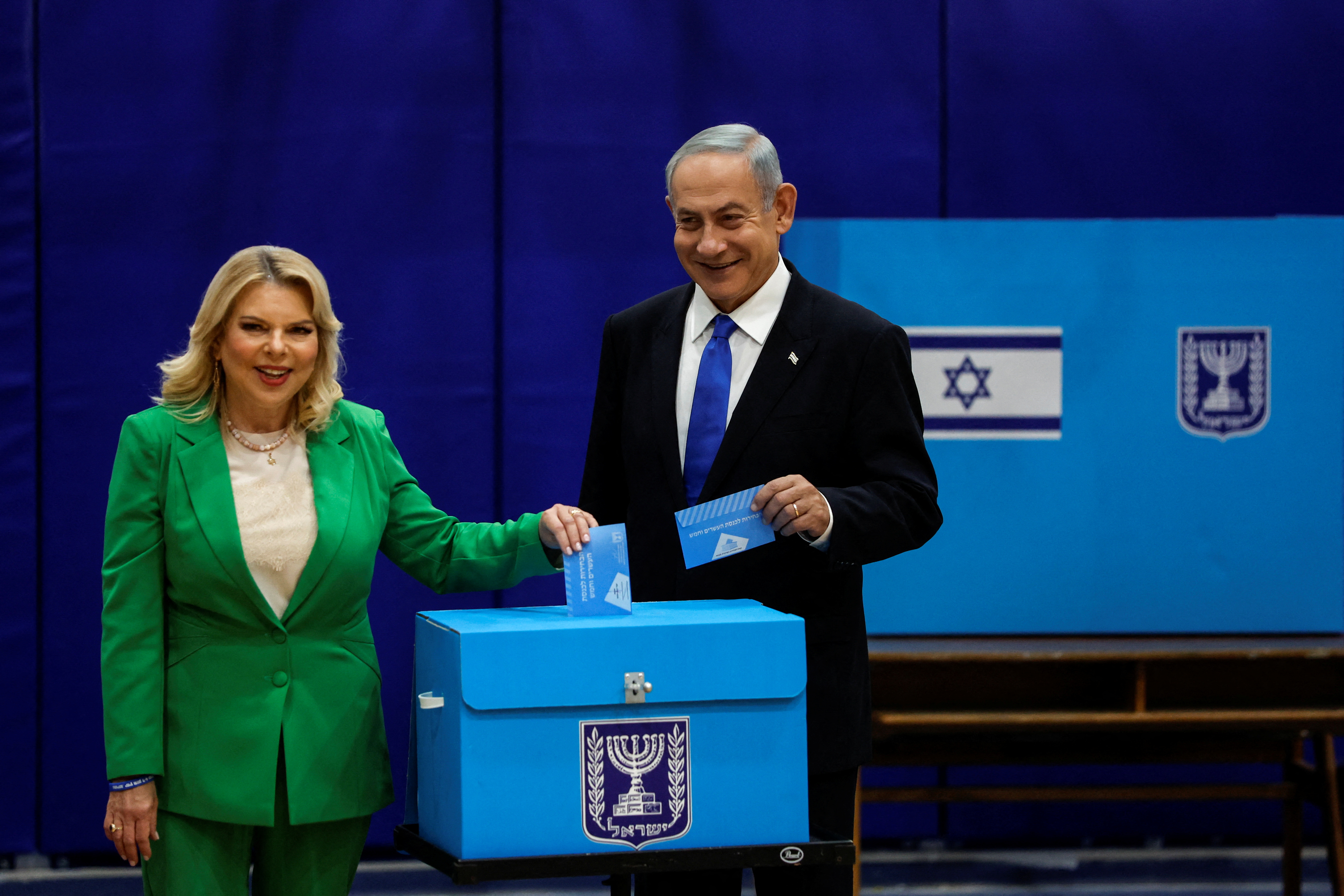 Former Israeli Prime Minister Benjamin Netanyahu stands with his wife Sarah as they vote on Israel's general election day at a polling station in Jerusalem, November 1, 2022 (REUTERS/Ammar Awad)