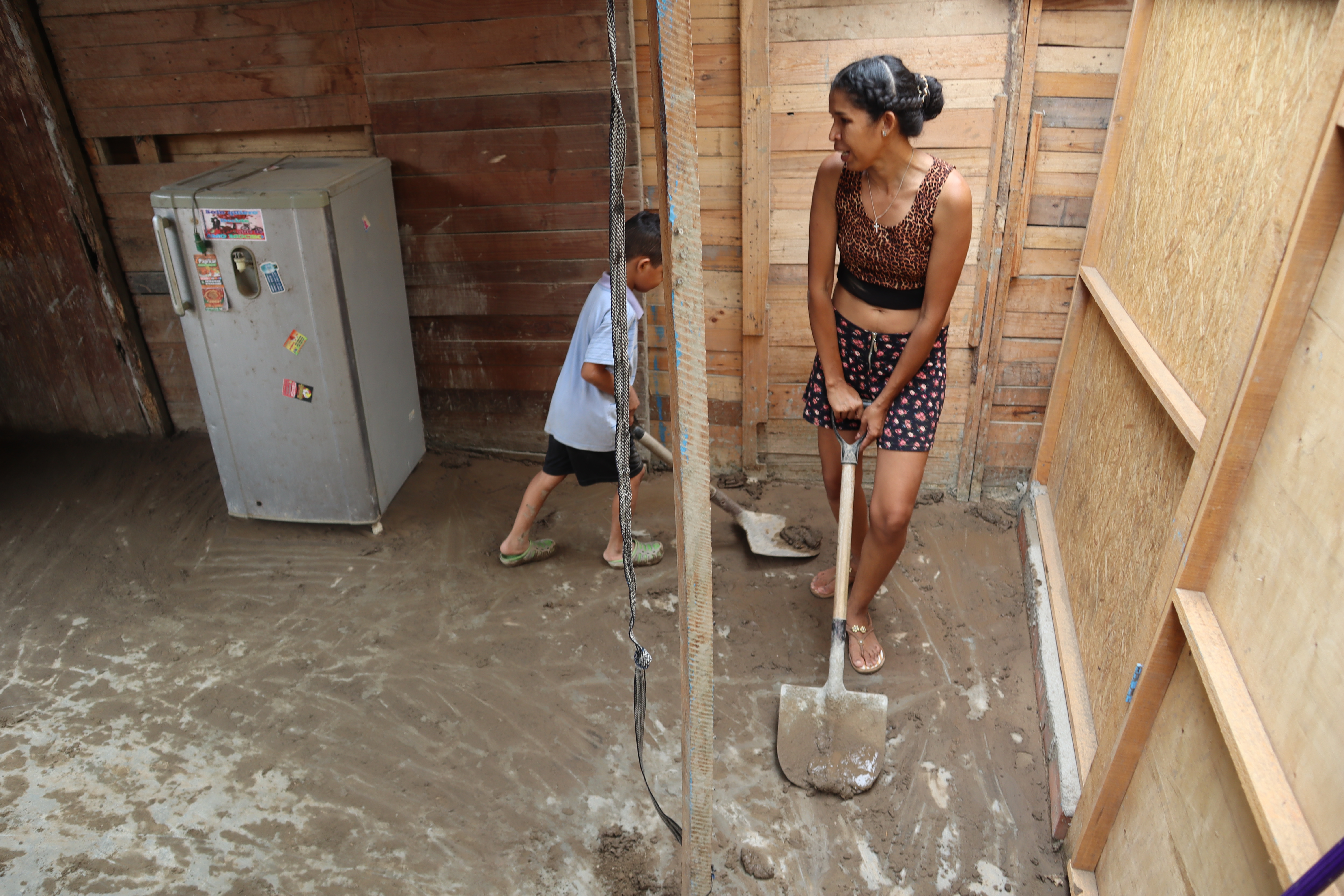 Madre e hijo intentan sacar el lodo de su vivienda tras el desborde del río Chillón. (Infobae/Paula Elizalde)