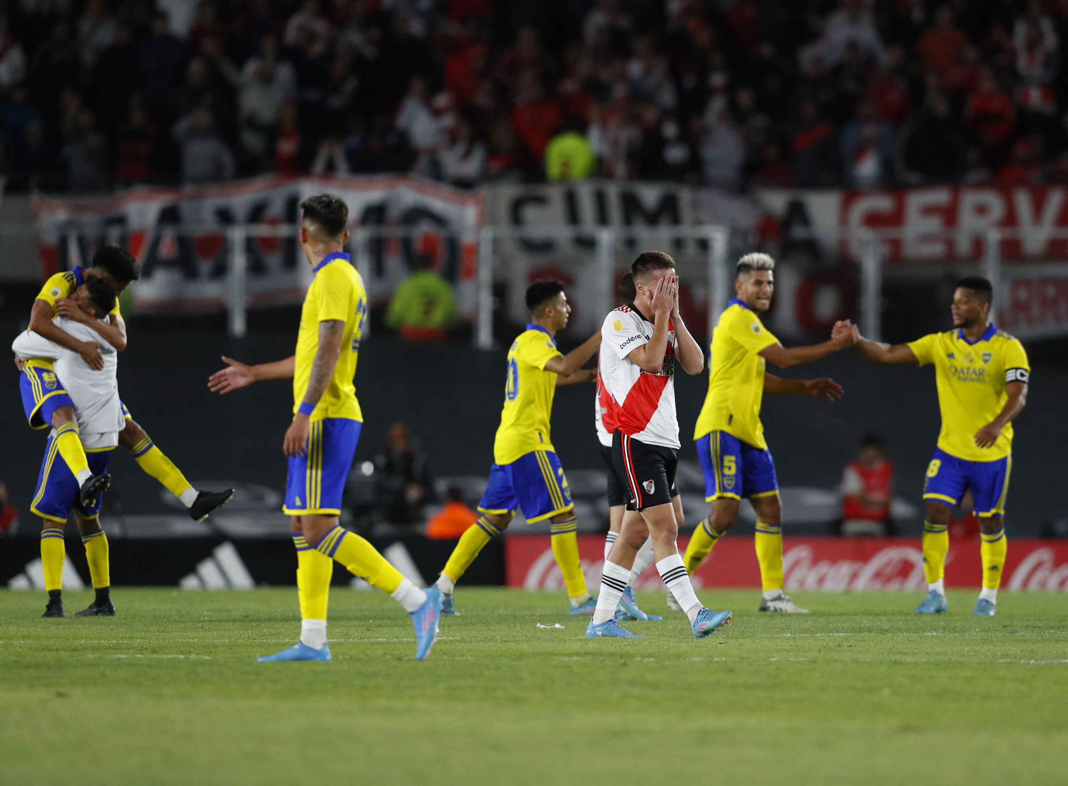 Contraste típico del fútbol: la felicidad de Boca y el dolor de unode los futbolistas de River tras el tropiezo (REUTERS/Agustin Marcarian)