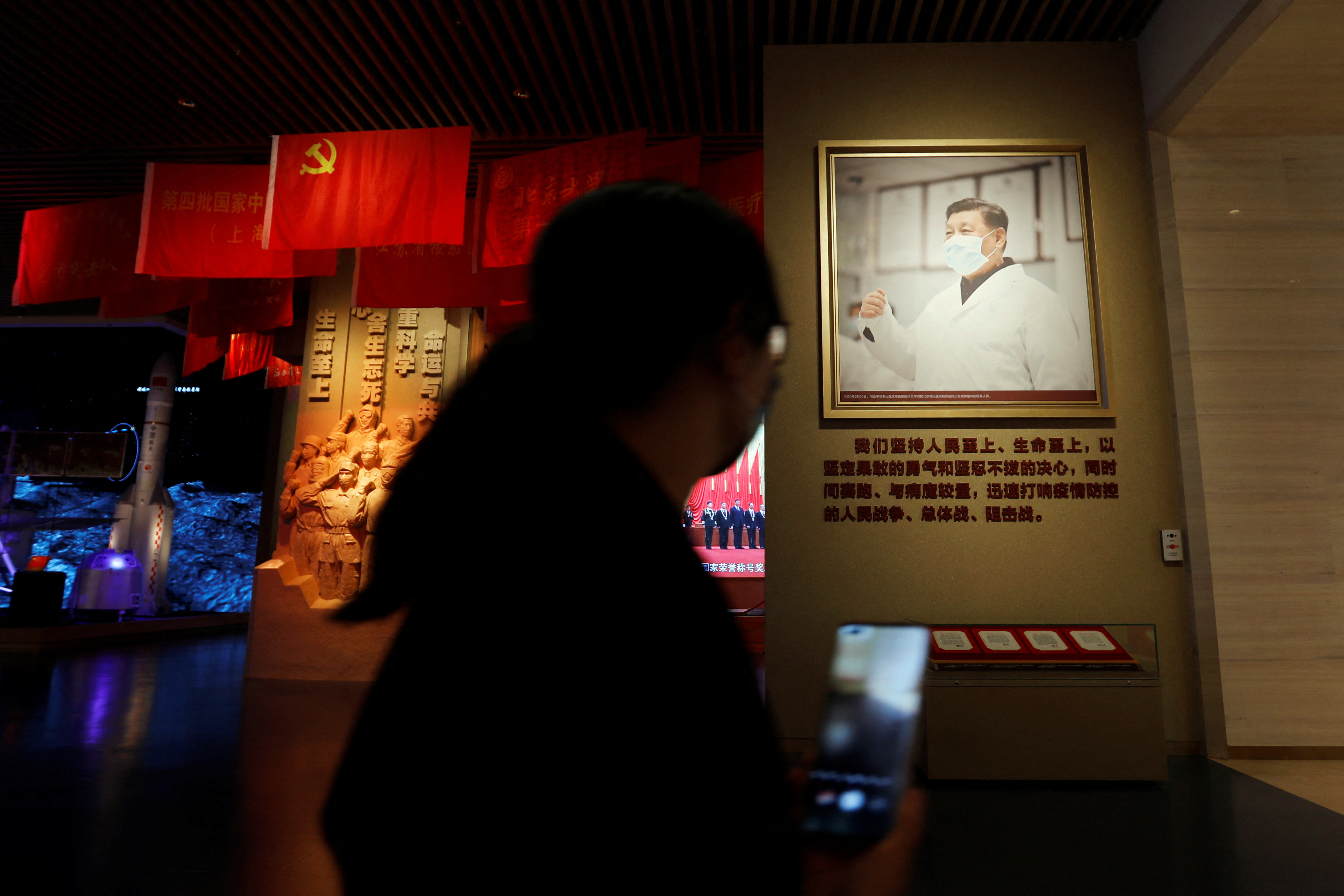 A visitor walks past an image of Chinese President Xi Jinping at a section on China's battle against the coronavirus disease (COVID-19), inside the Museum of the Communist Party of China in Beijing, China, 13 October 2022. REUTERS/Florence Lo