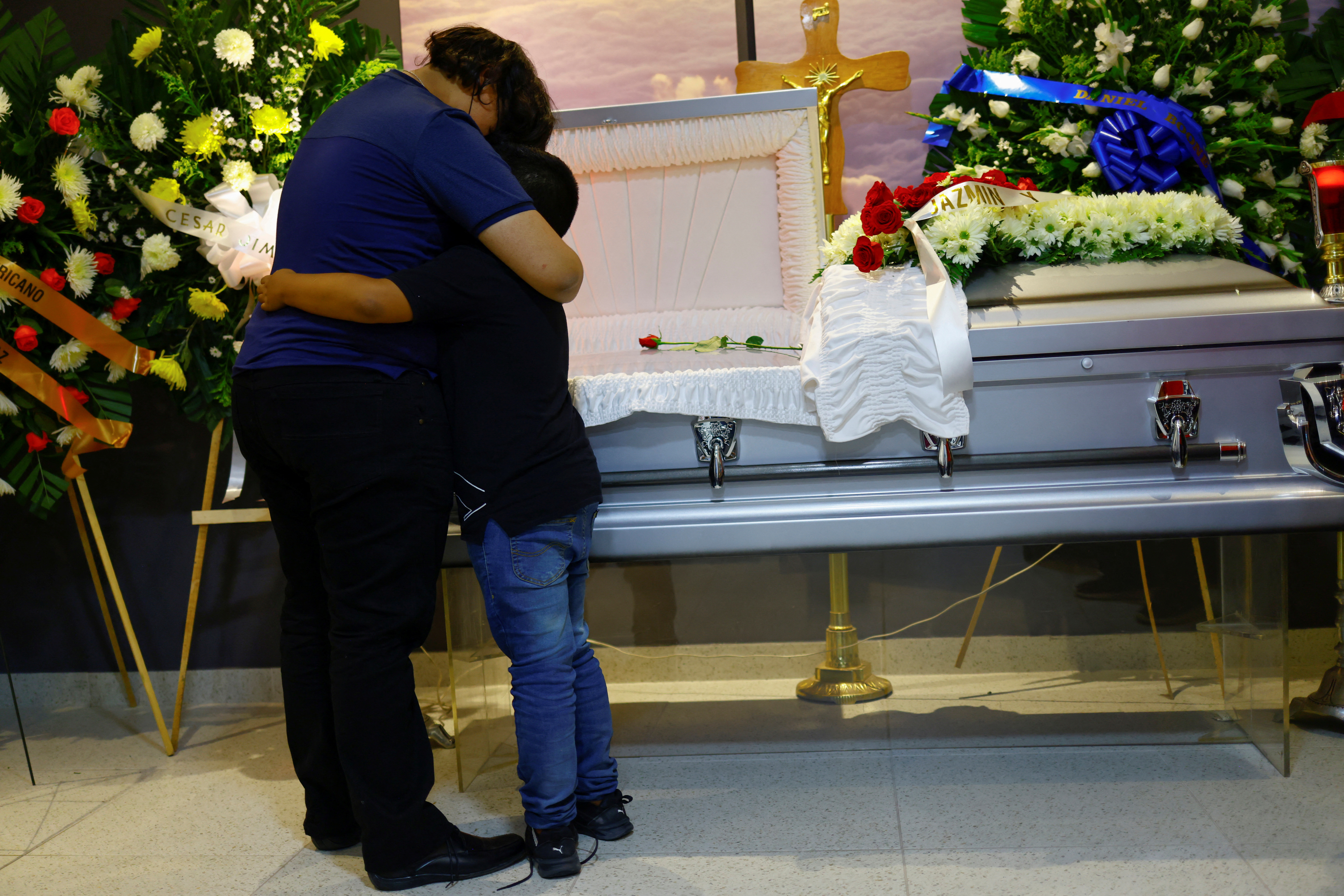 The children of Manuel Alejandro Arriaga, who was killed last week along with three coworkers of Switch radio station, hug in front of his coffin during the funeral in Ciudad Juarez, Mexico, August 15, 2022. REUTERS/Jose Luis Gonzalez