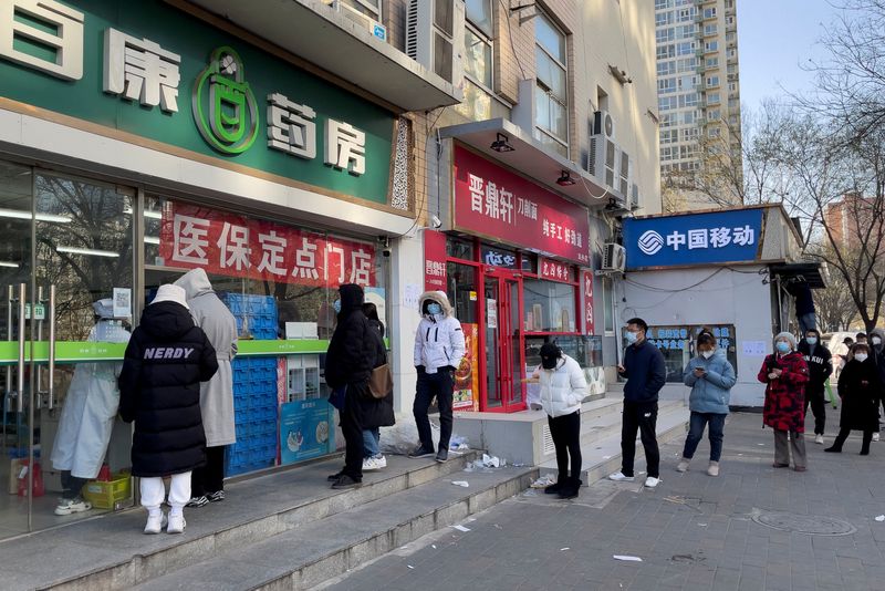Personas con mascarillas hacen cola frente a una farmacia para comprar productos mientras continúan los brotes de la enfermedad por coronavirus (COVID-19) en Pekín, China, el 6 de diciembre de 2022. REUTERS/Alessandro Diviggiano