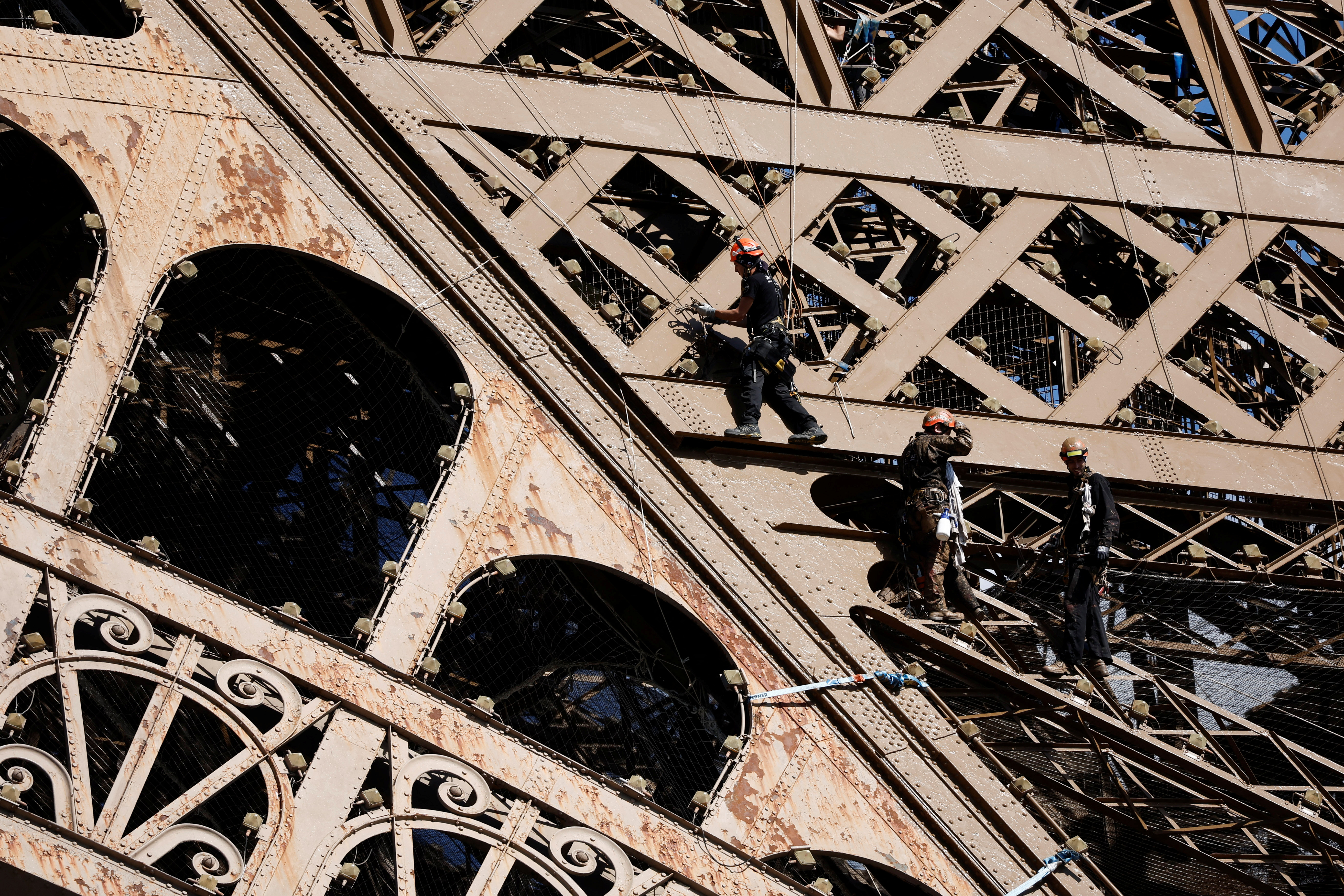 Workers work on the Eiffel tower during the 20th campaign of painting and stripping in Paris, France, July 5, 2022. REUTERS/Benoit Tessier