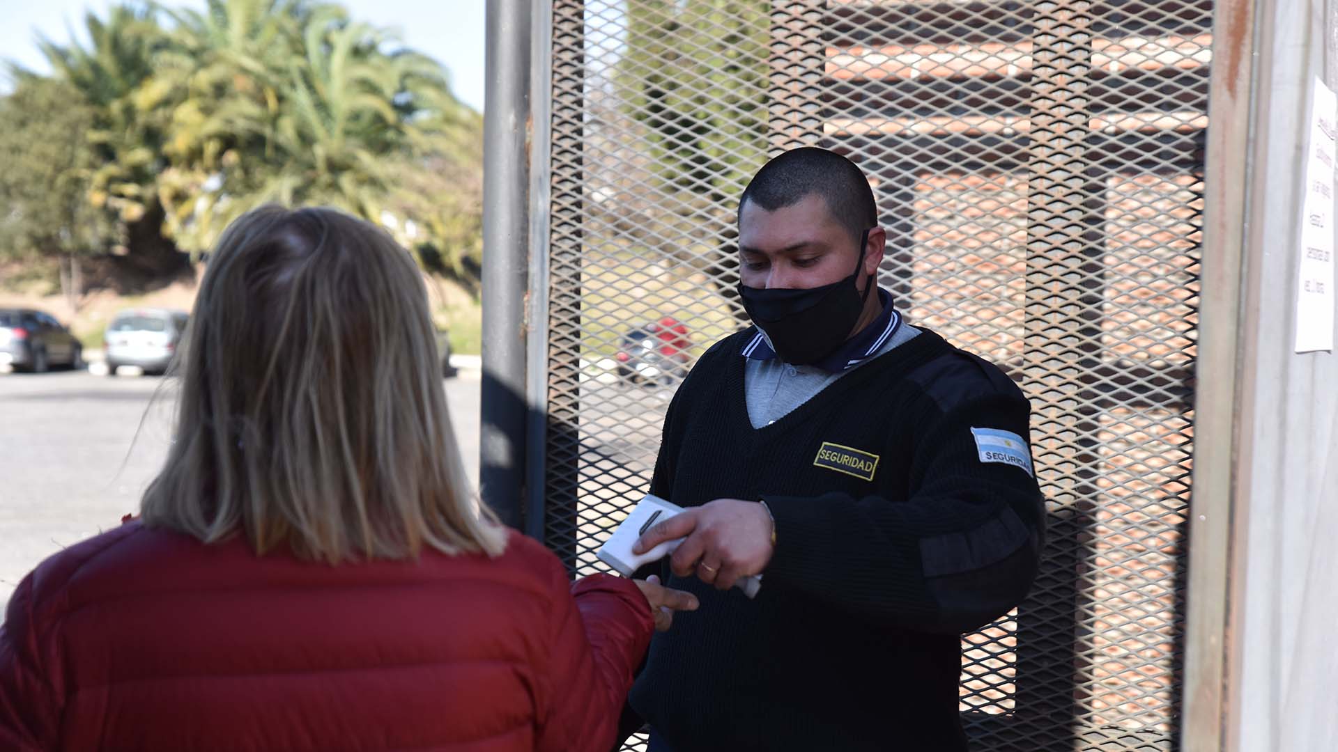 Personal de seguridad le toma la temperatura corporal a los visitantes