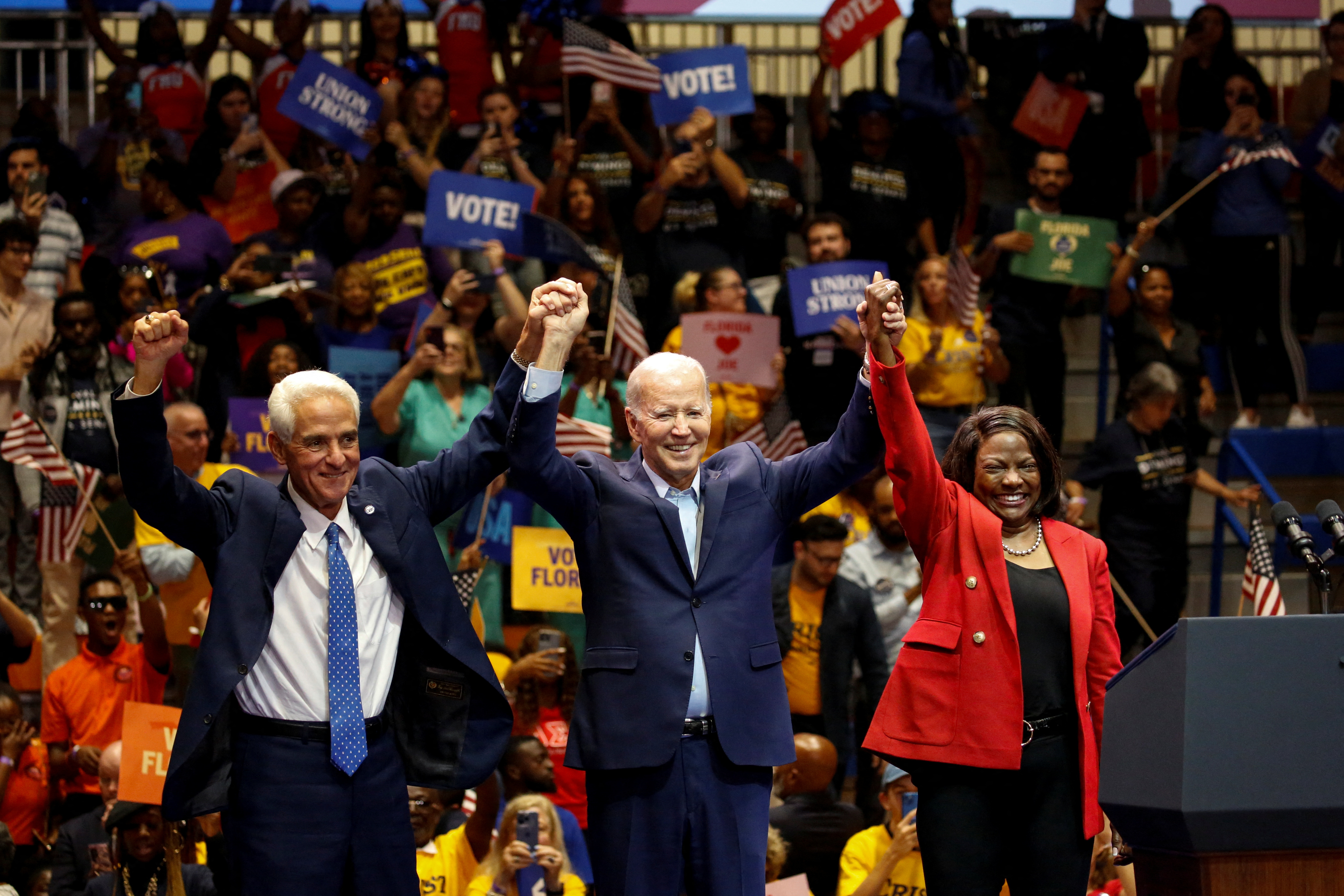 El presidente Joe Biden levanta las manos del candidato al Congreso, Val Demings, y a gobernador, Charlie Crist, en un acto de campaña realizado en  Miami Gardens, Florida. (REUTERS/Marco Bello)